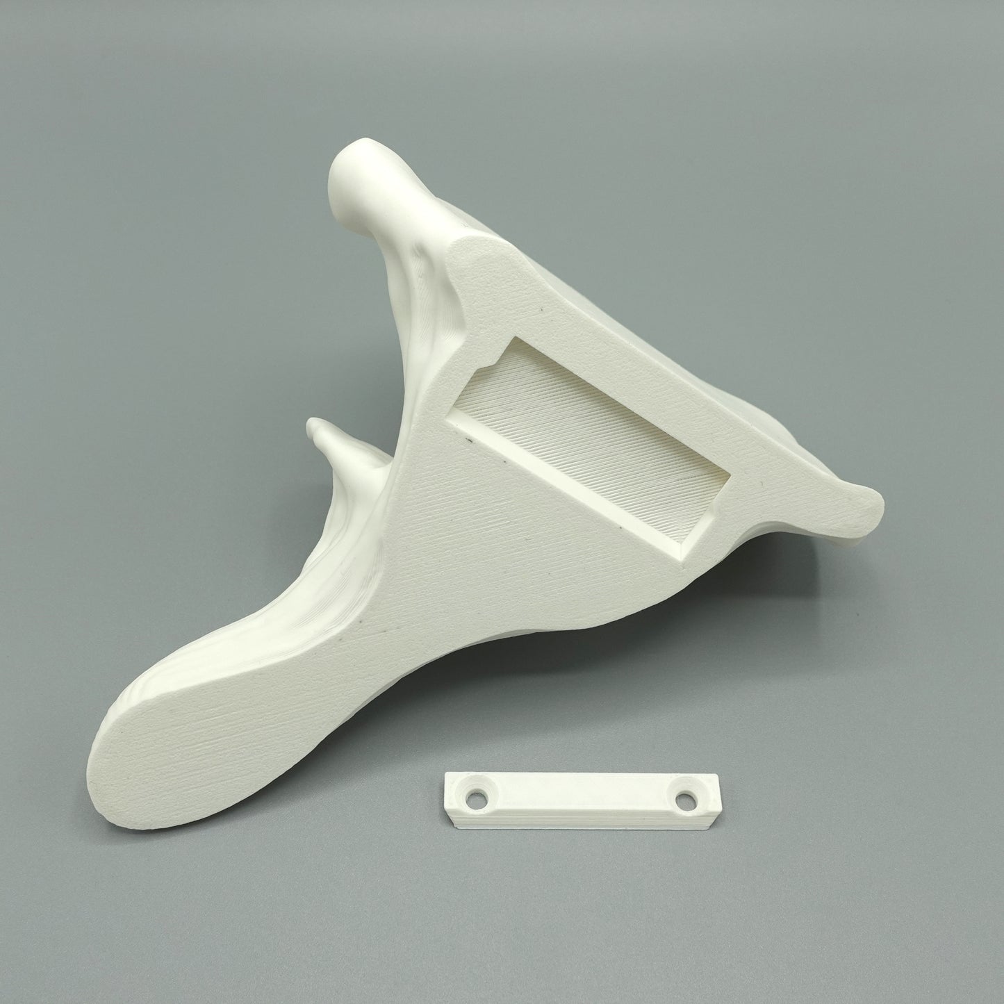 Detailed view of the underside of a white Oyster Floating Shelf, revealing its unique design with a mounting slot for easy installation.