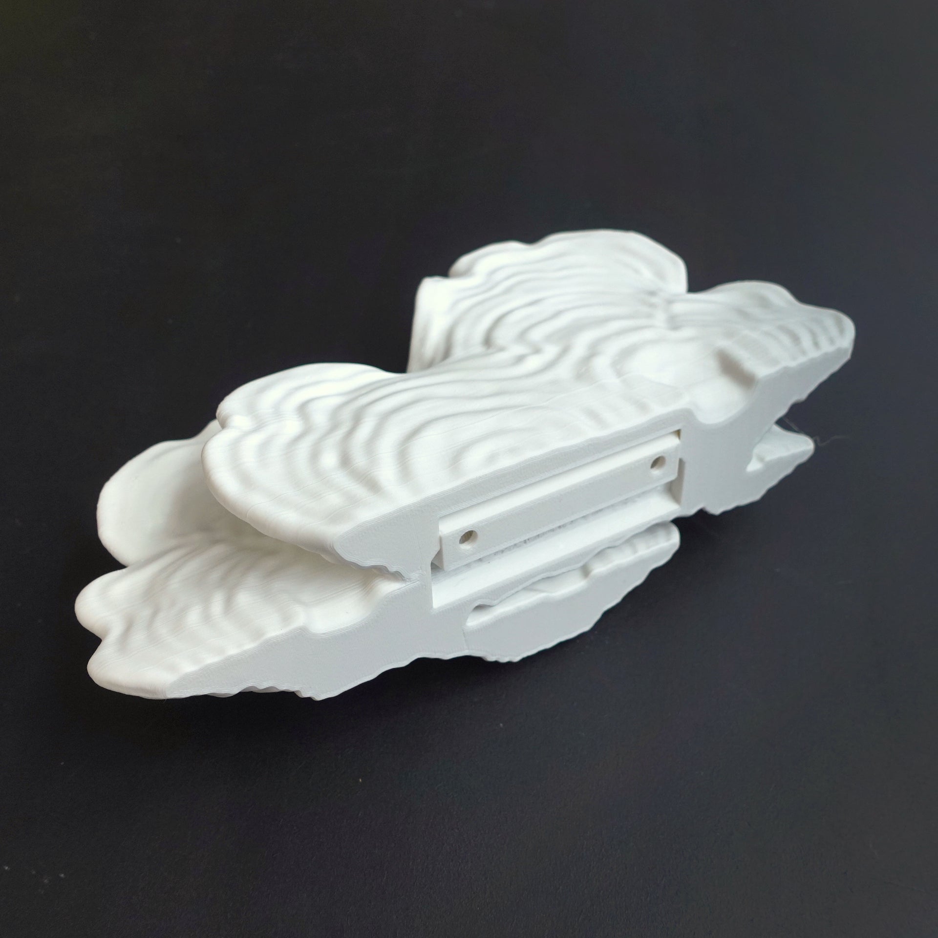 Detailed view of a white Ostrea Mushroom Floating Shelf from beneath, showcasing its intricate design and mounting options.