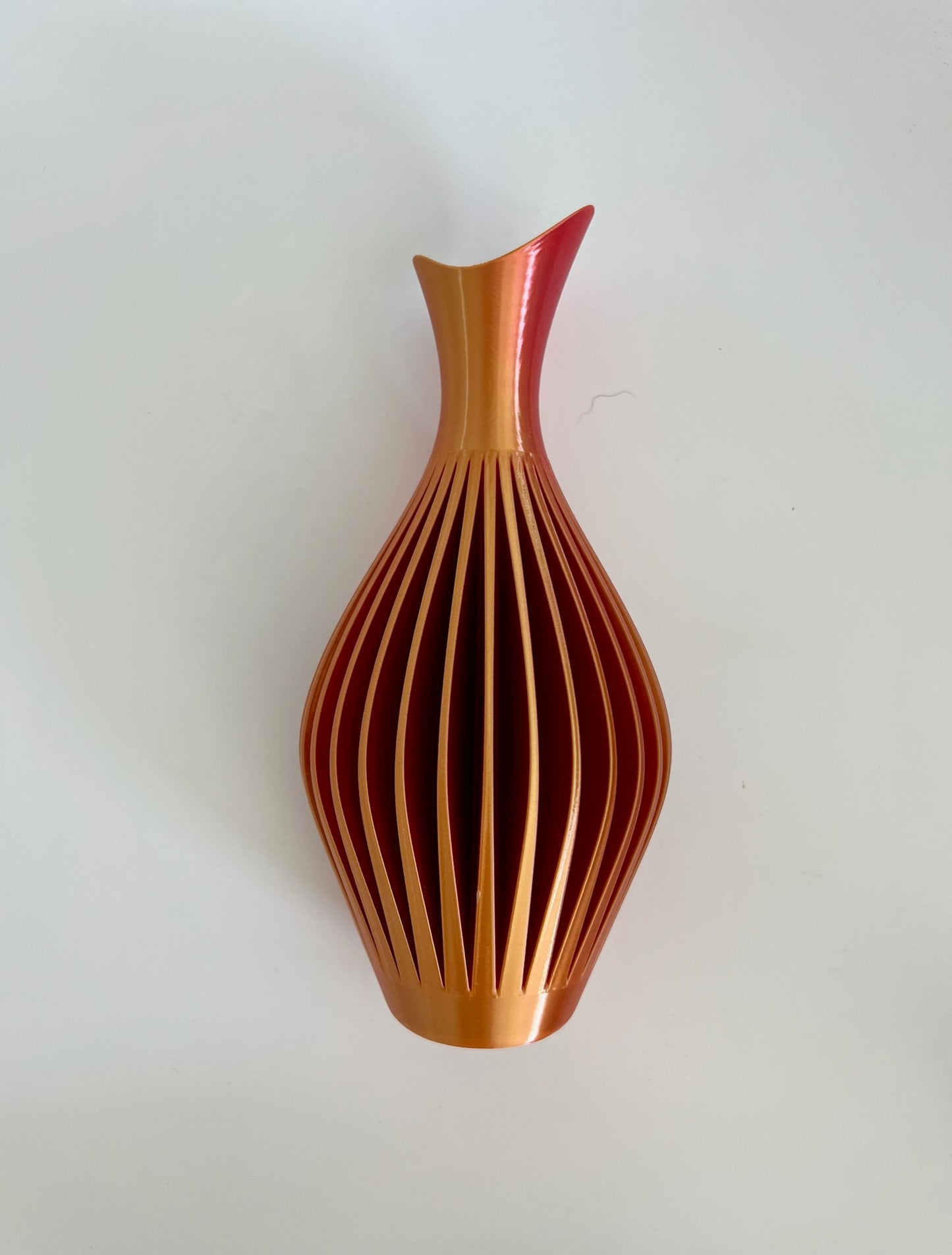Eye-catching orange and red wall vase elegantly shaped, adorned with fresh floral accents.