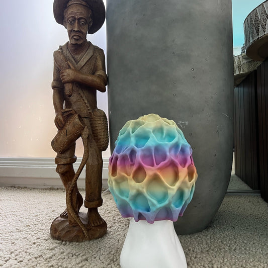 Colorful Morel-inspired illuminated table lamp next to a decorative wooden figure and potted plant.