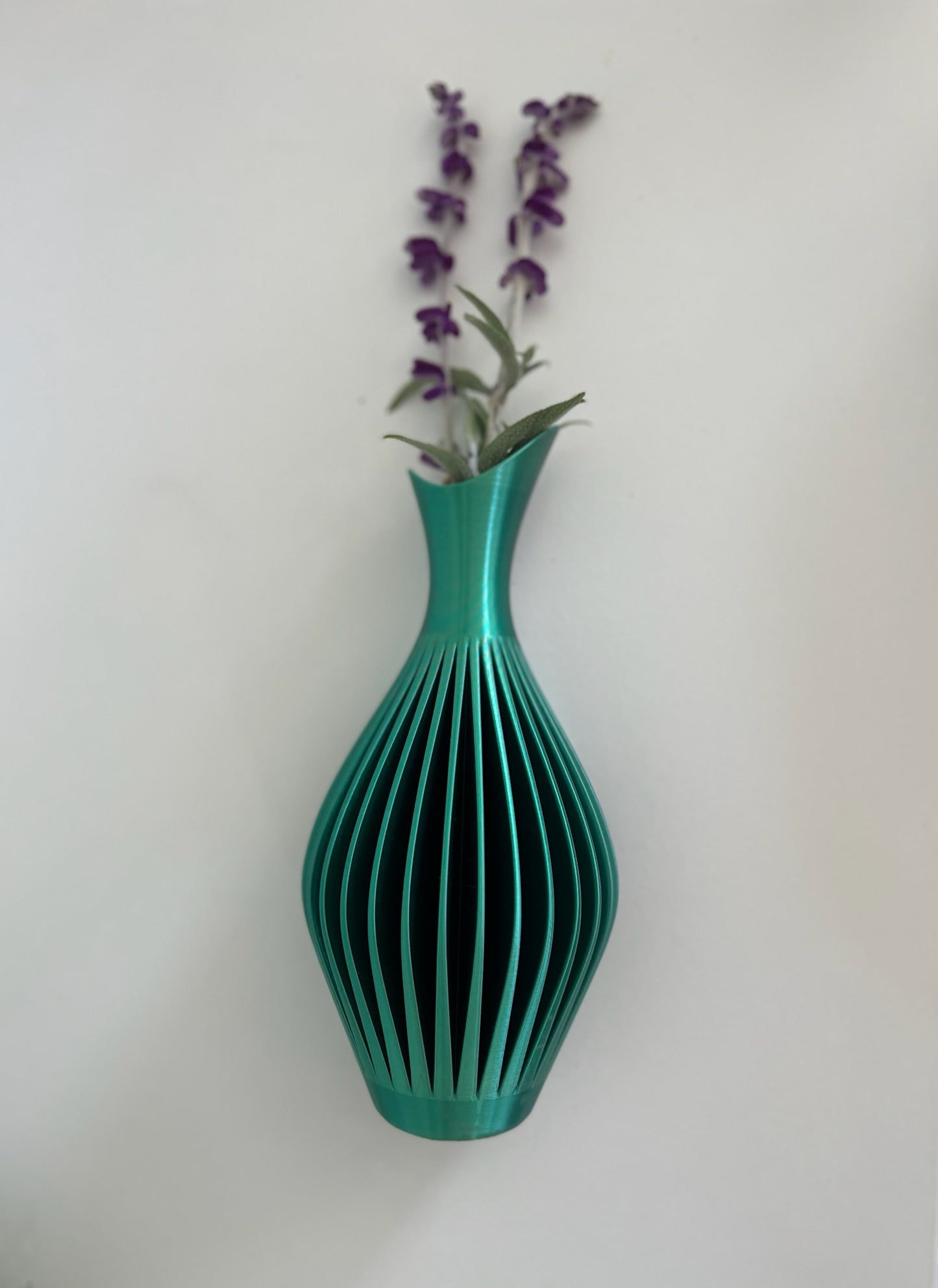 Sleek turquoise modern wall vase filled with purple flowers, enhancing a contemporary interior.