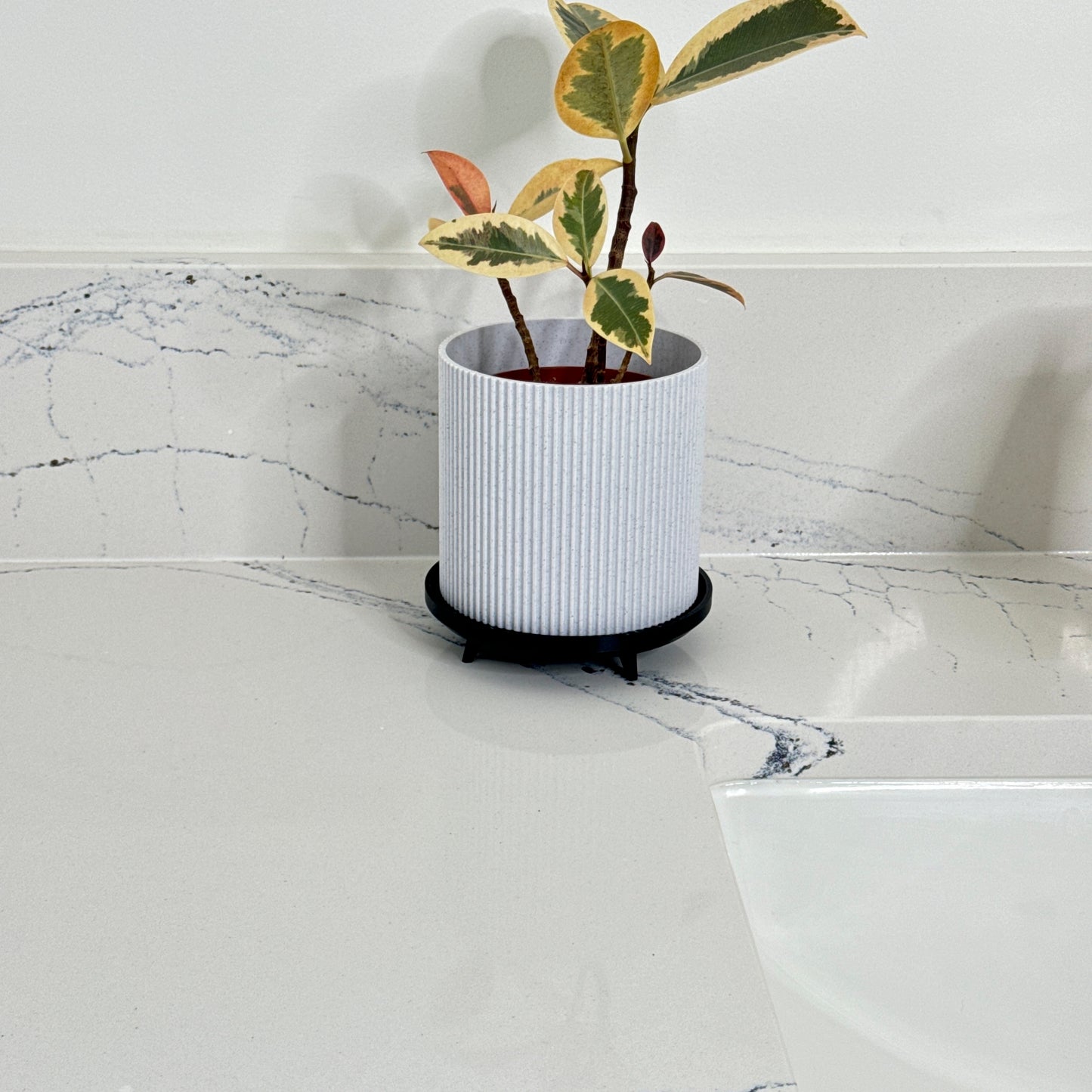 Elegant indoor planter with stand – A sleek and modern planter featuring a ribbed design and rich marble tones, complete with a minimalist black stand for a sophisticated look.
