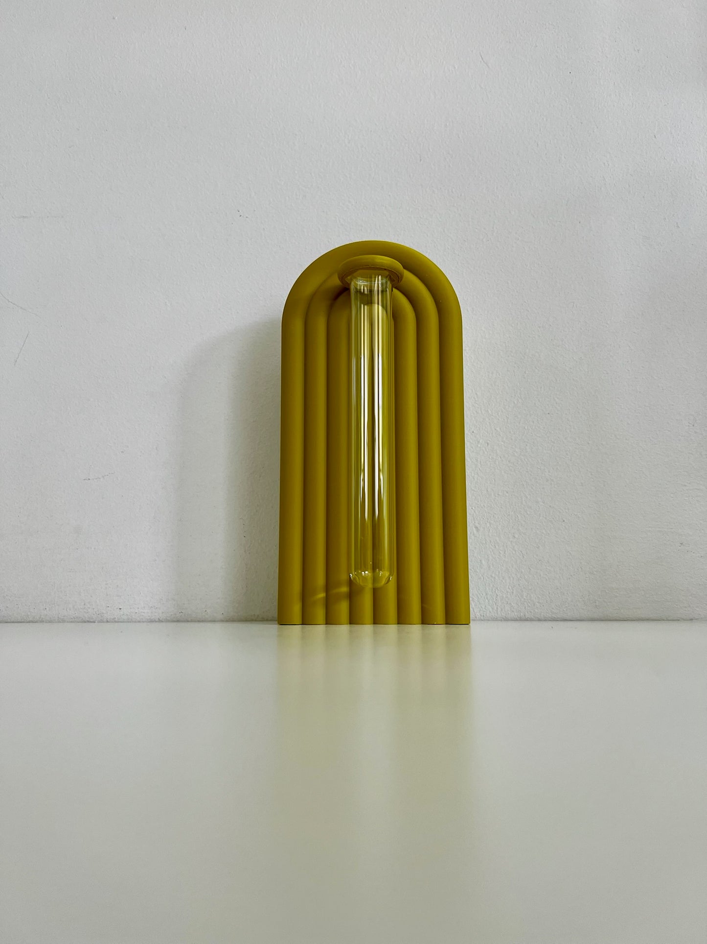 Sleek yellow propagation bookend, featuring a glass tube for plant propagation against a plain backdrop.