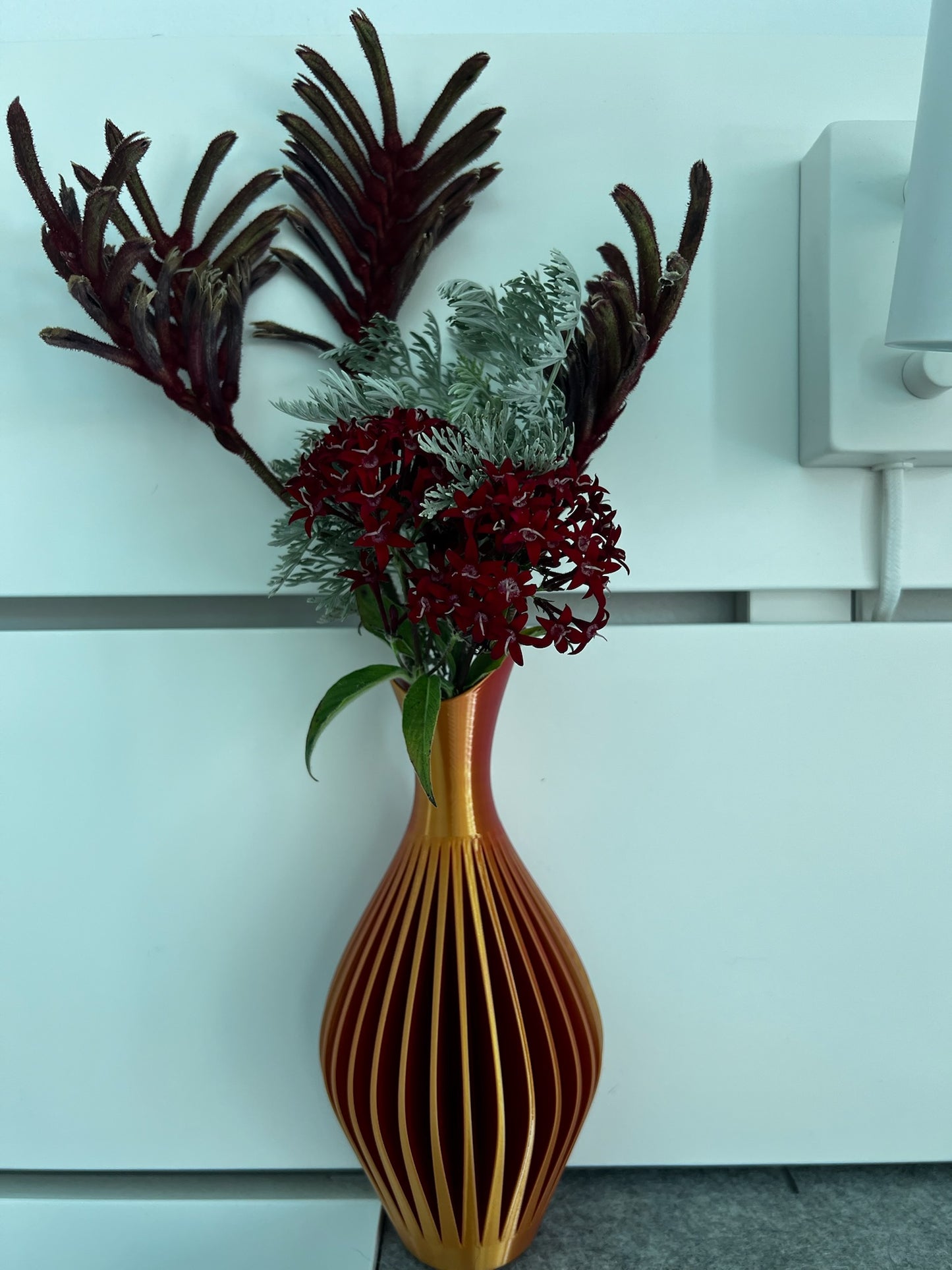Chic orange wall vase displaying vibrant flowers, perfect for adding color and charm.
