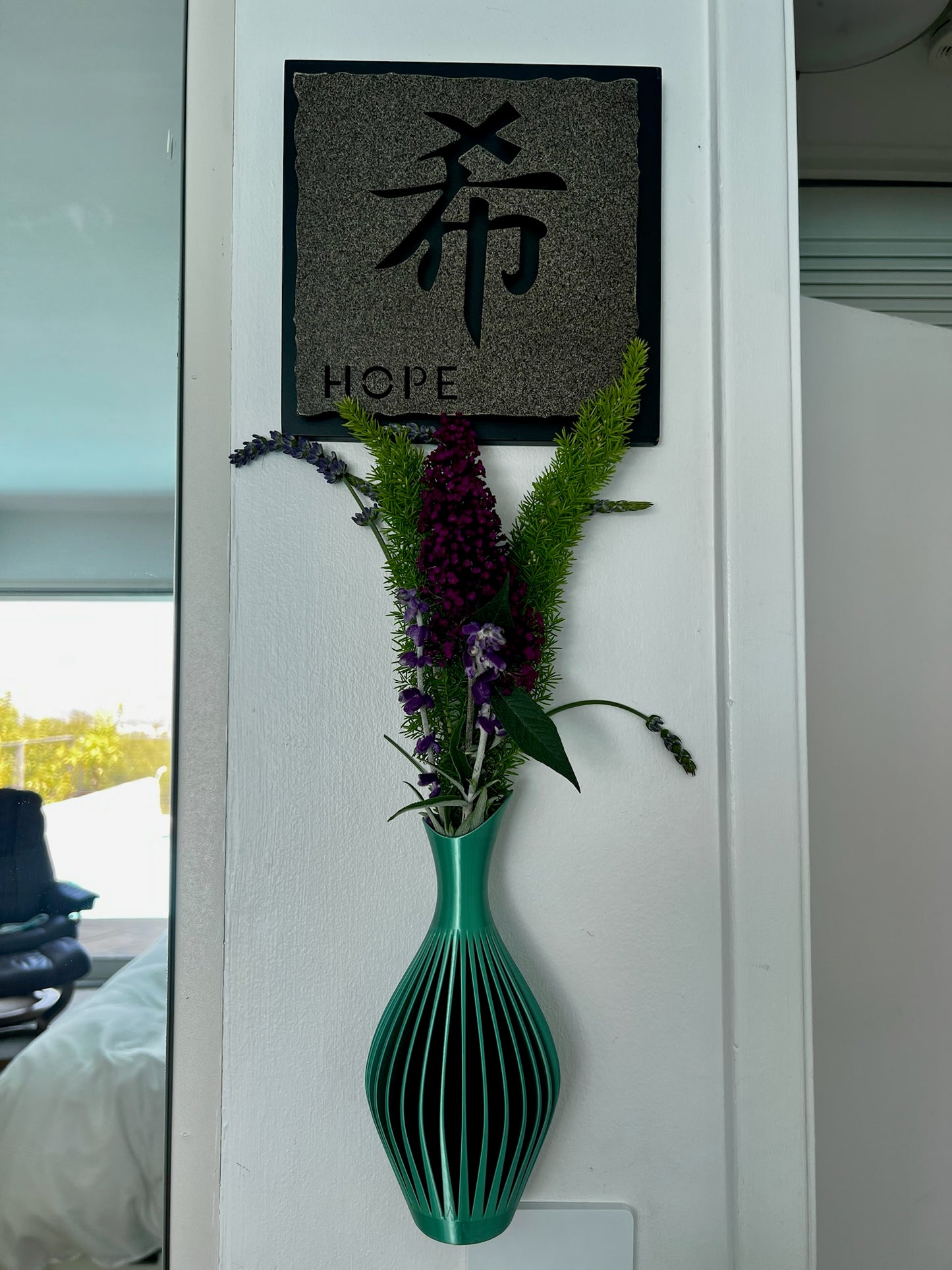 Sophisticated green wall vase adorned with fresh flowers, enhancing the decor of the room.
