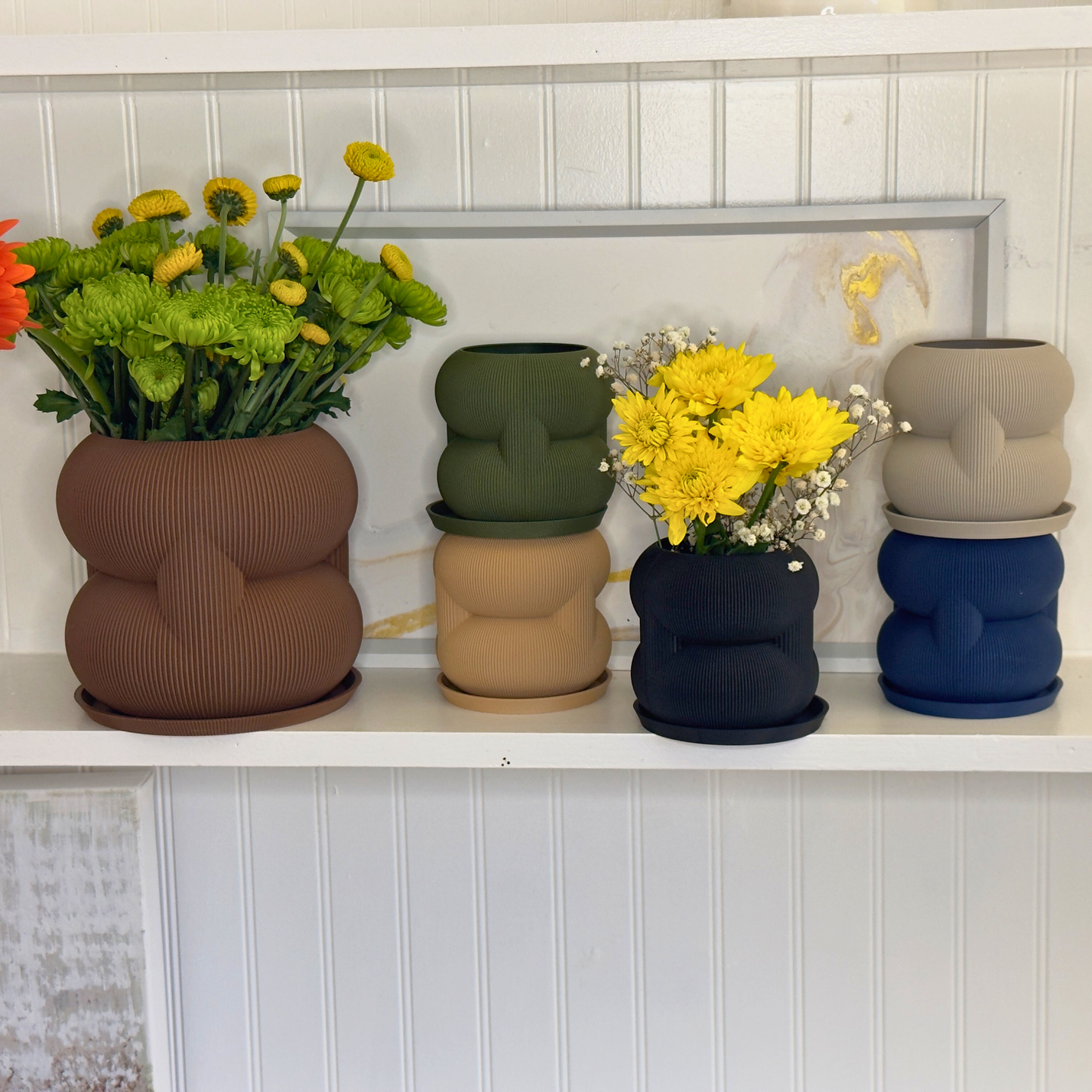 An elegant display of various rounded stacked planters in multiple colors, each filled with fresh flowers, highlighting stylish indoor gardening options.
