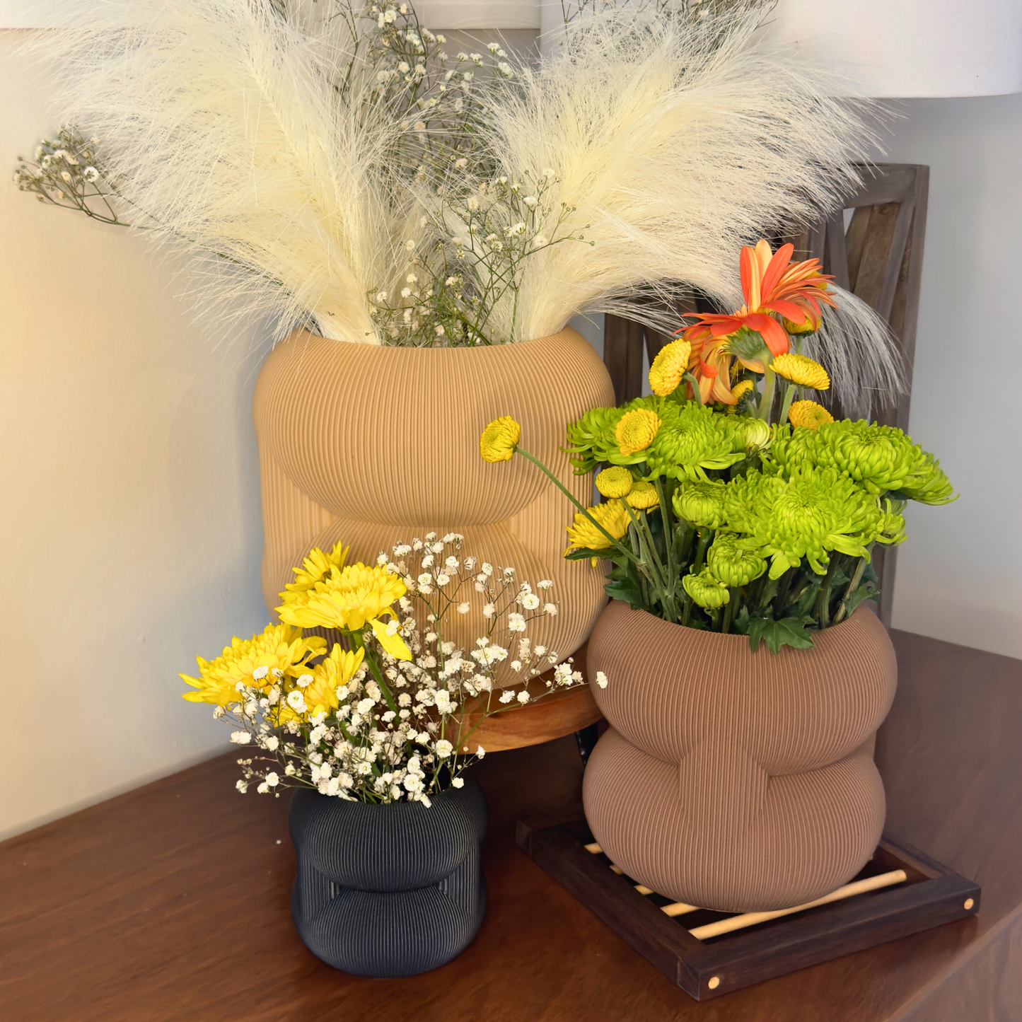 Stylish rounded stacked planters in warm tones with vibrant artificial flowers, showcasing a modern decorative arrangement for home decor.