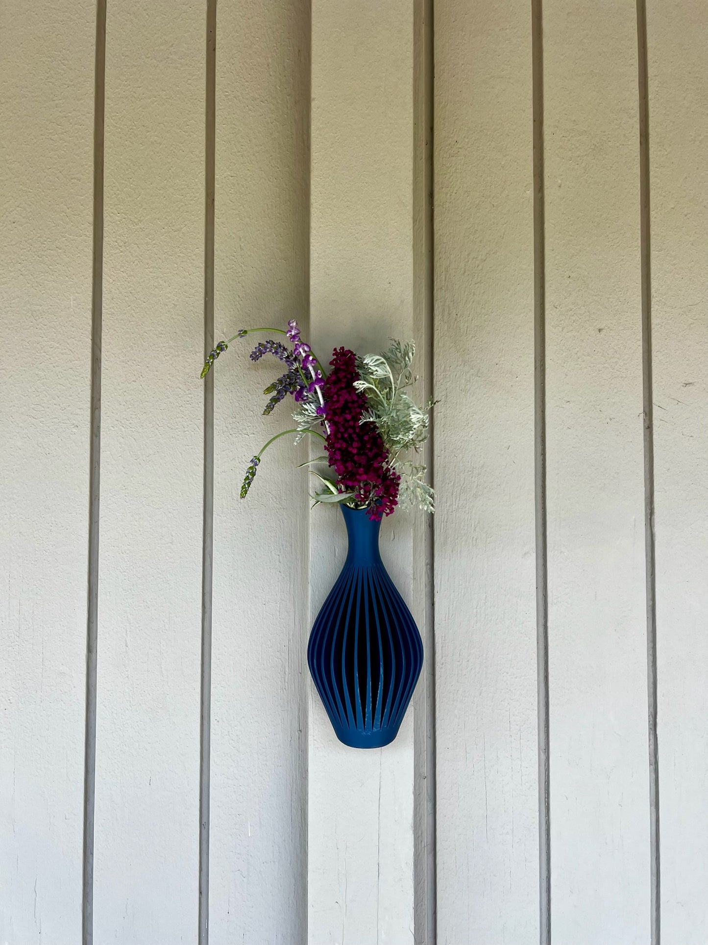 Vividly colored turquoise wall vase with a floral arrangement, creatively placed on a clean background.