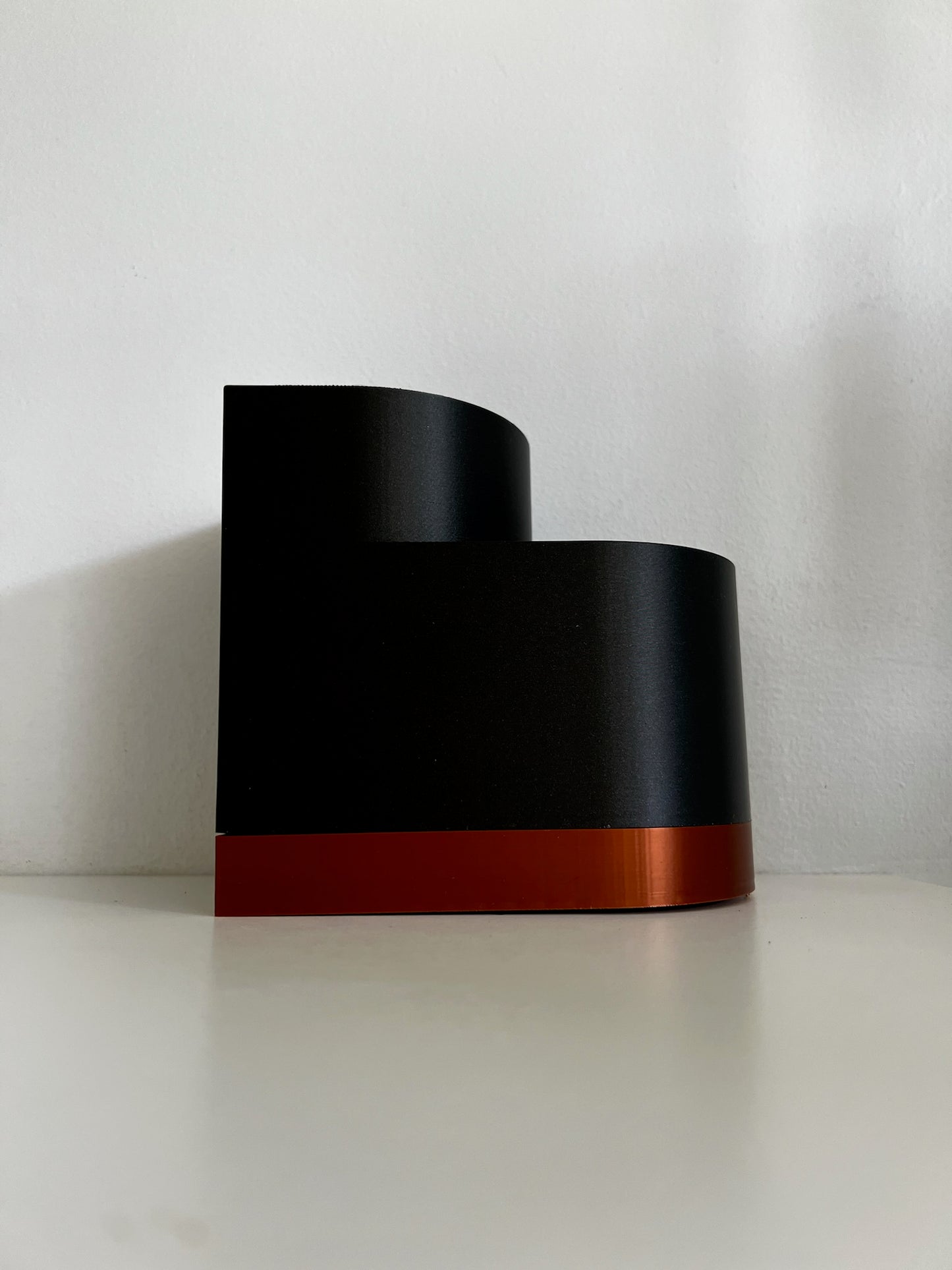 Dark side profile of a black double layer planter, featuring a clean design with an orange border at the bottom.