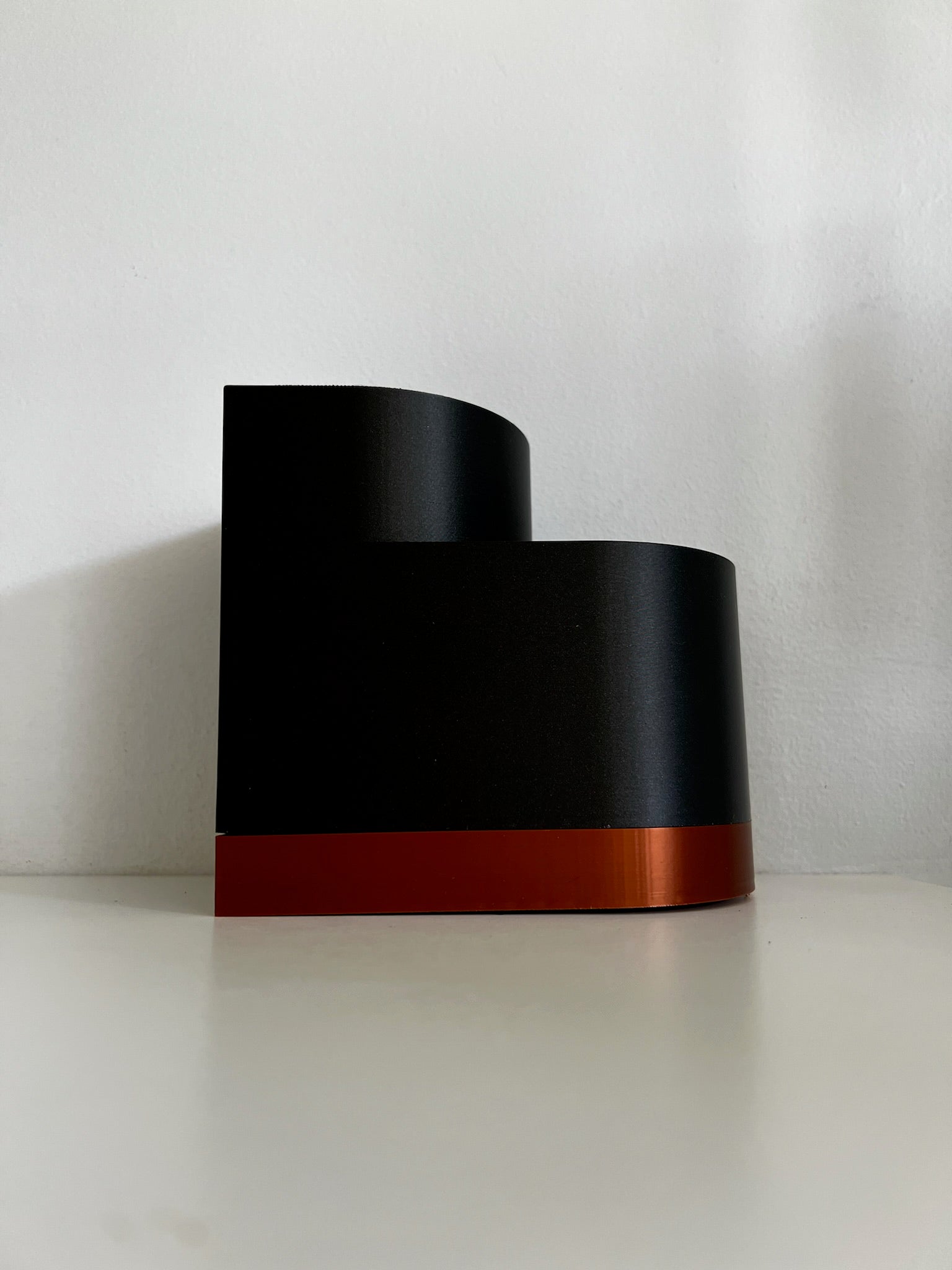 Dark side profile of a black double layer planter, featuring a clean design with an orange border at the bottom.