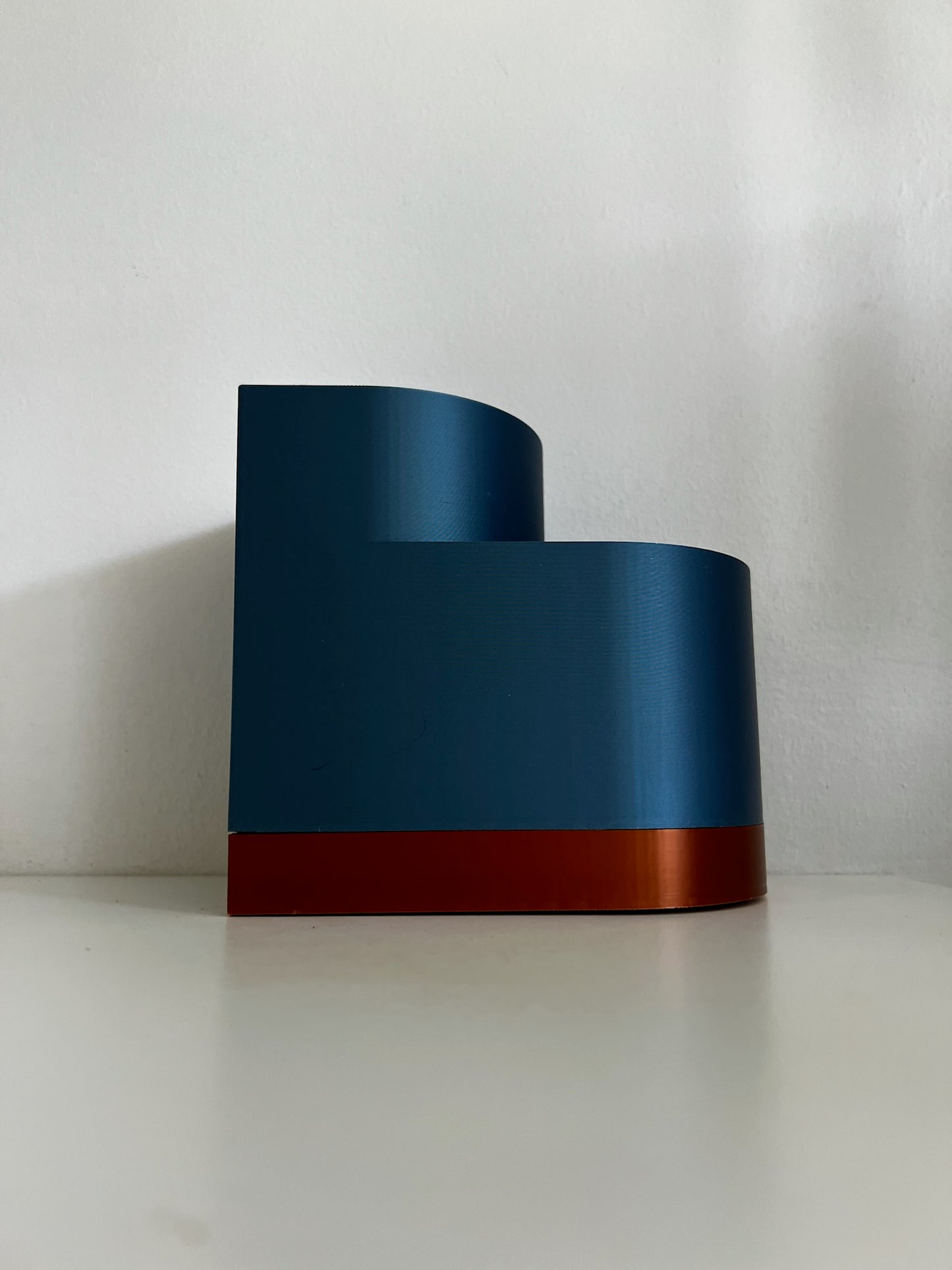 Side view of a blue double layer planter on a table, showcasing its modern lines and stylish orange accent.