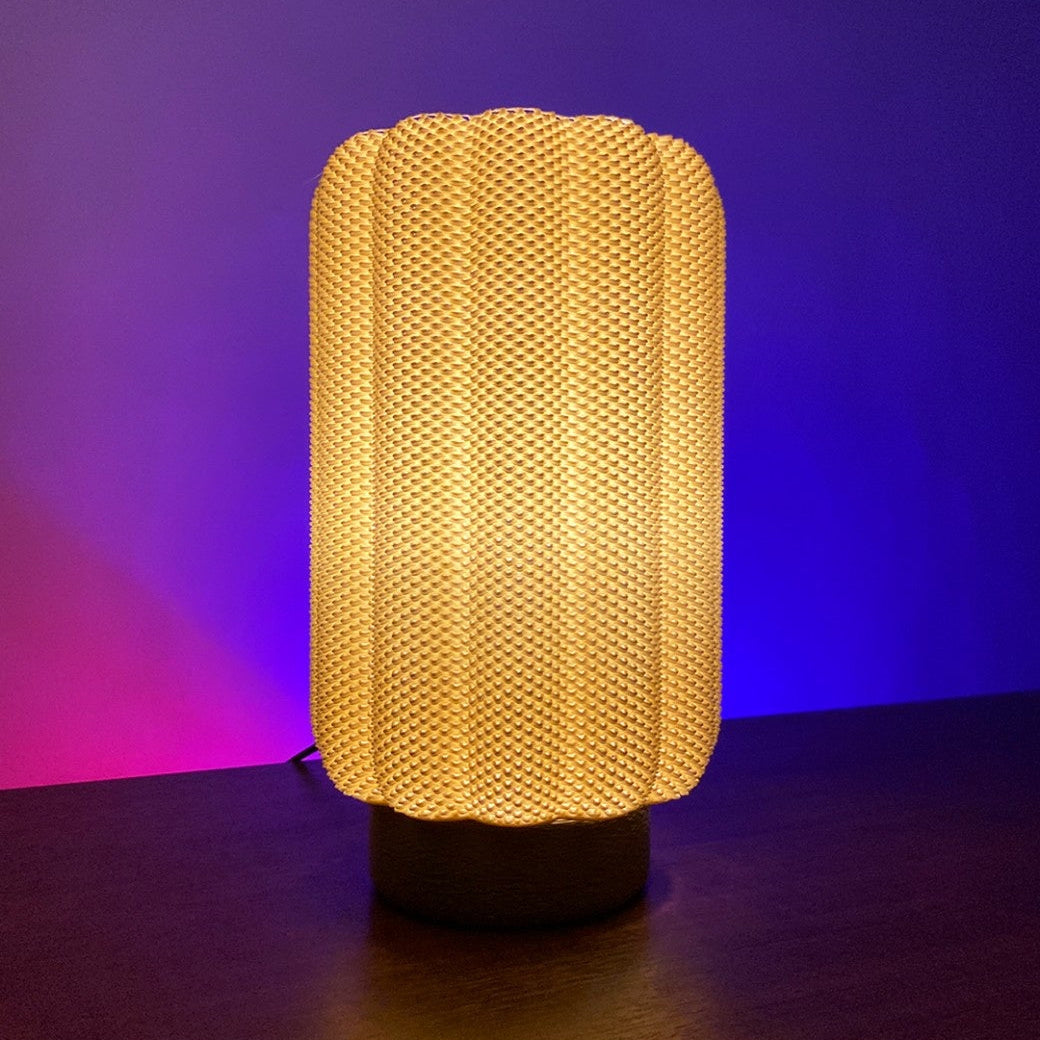 CARLA Table Lamp emitting warm orange light, showcasing its stylish textured design against a purple backdrop, ideal for creating a relaxing atmosphere.