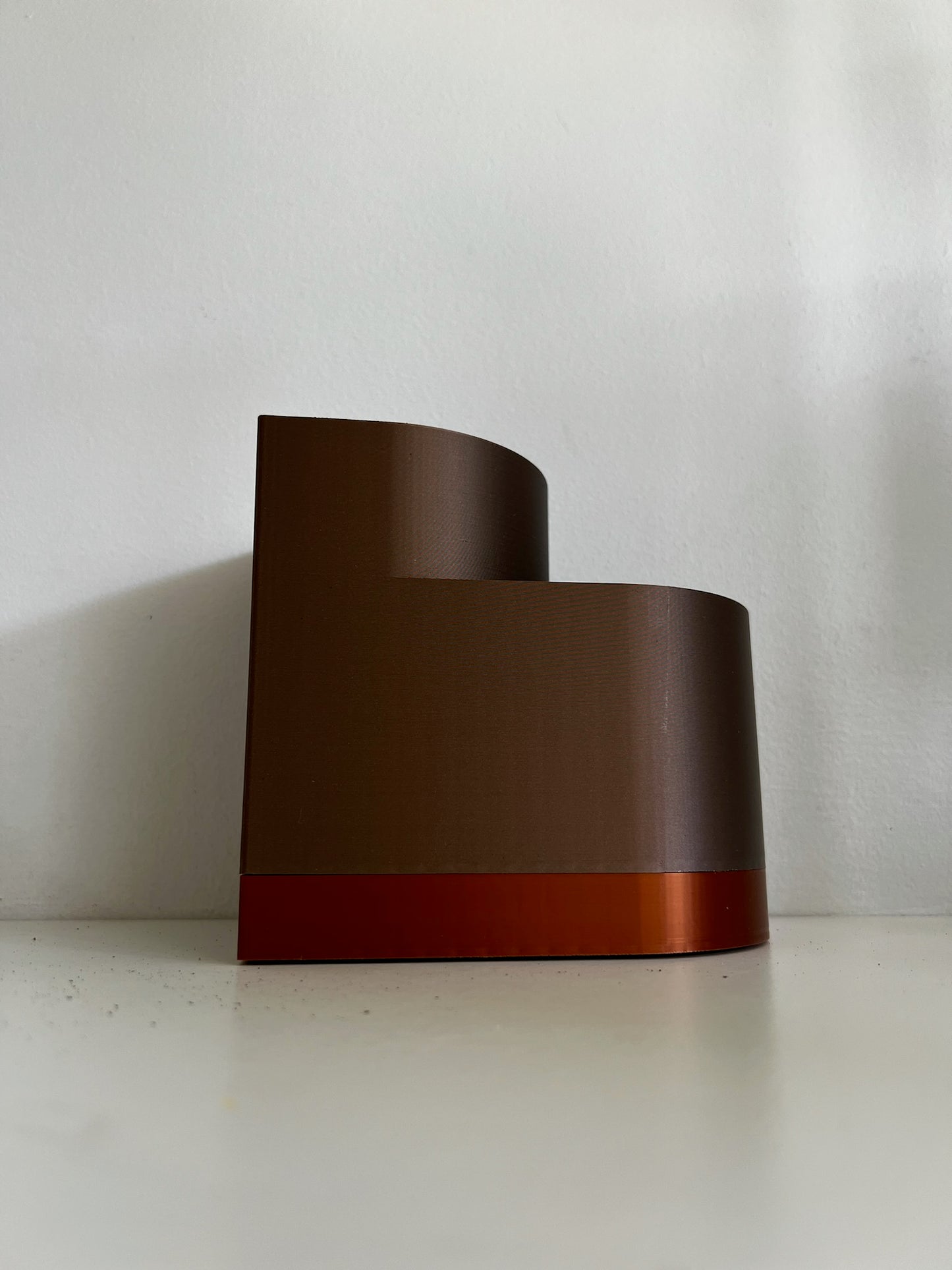 Side profile image of a brown double layer planter, emphasizing its unique shape and elegant orange bottom.