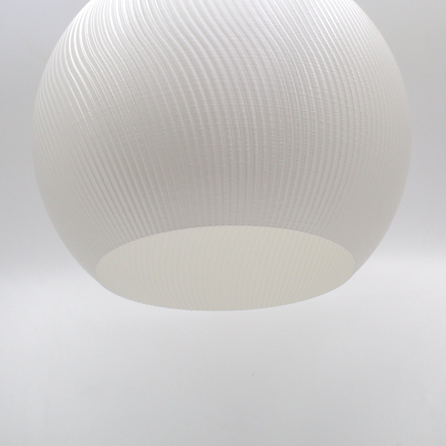 Stylish close-up of a white lampshade featuring a softly curved design and textured exterior.