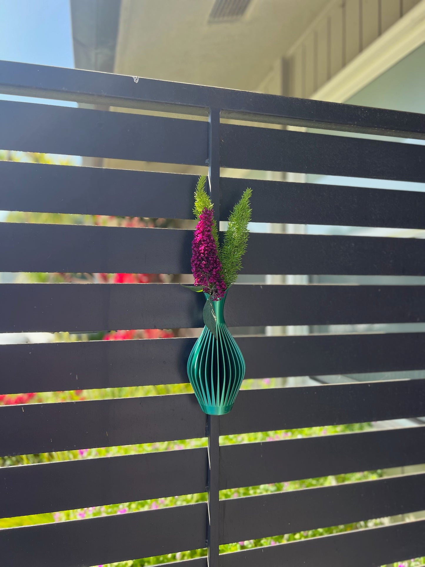 Stylish and modern turquoise wall vase showcasing a floral arrangement on a white wall.