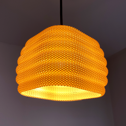 Daira Lampshade in vibrant orange, showcasing a sophisticated woven texture that creates elegant shadows when illuminated.