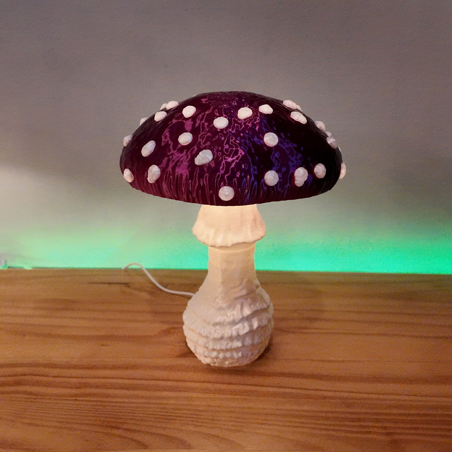A single purple Amanita fungi lamp with a glowing cap, resting on a wooden surface, creating a magical ambiance.