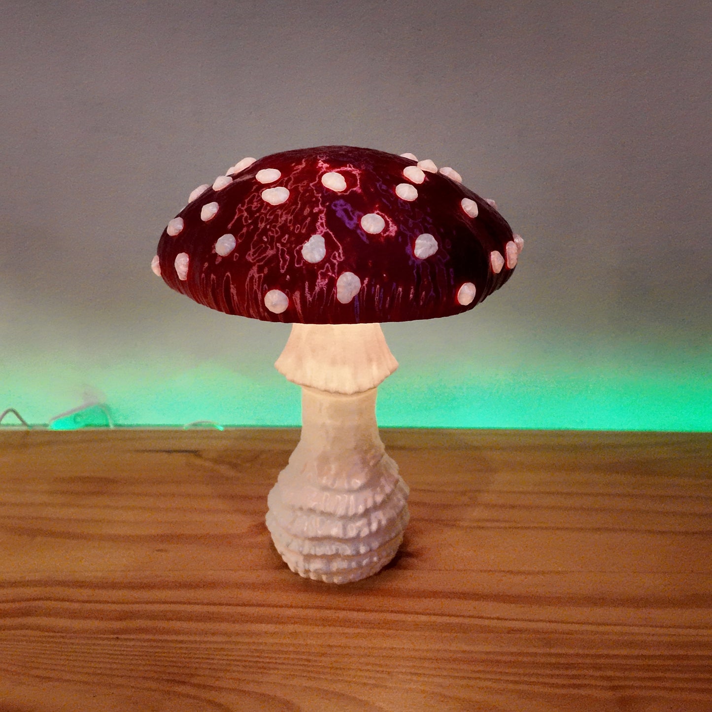 A red Amanita fungi lamp with glowing accents, positioned elegantly on a wooden table, adding charm to the decor.