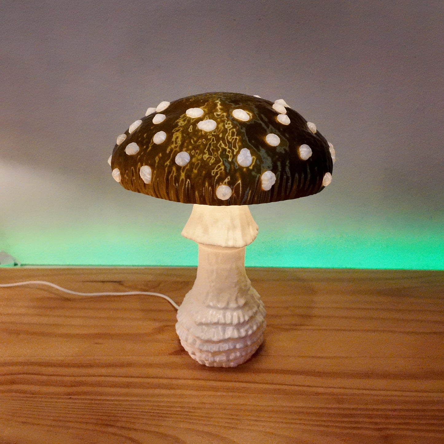 A green Amanita fungi lamp radiating light, featuring a whimsical design, resting on a wooden surface with a soft background glow.