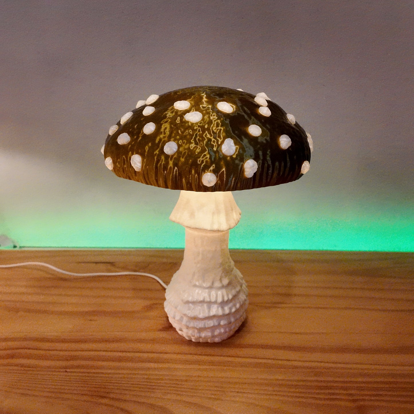 A glowing green Amanita fungi lamp showcasing its unique cap and stem design, set against a softly lit background.