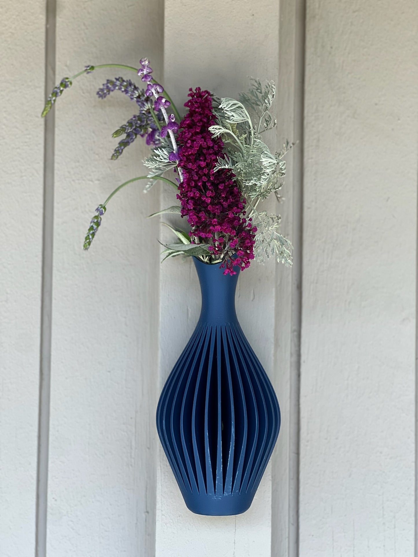 Modern green wall vase decorated with colorful flowers, enhancing the ambiance of the room.