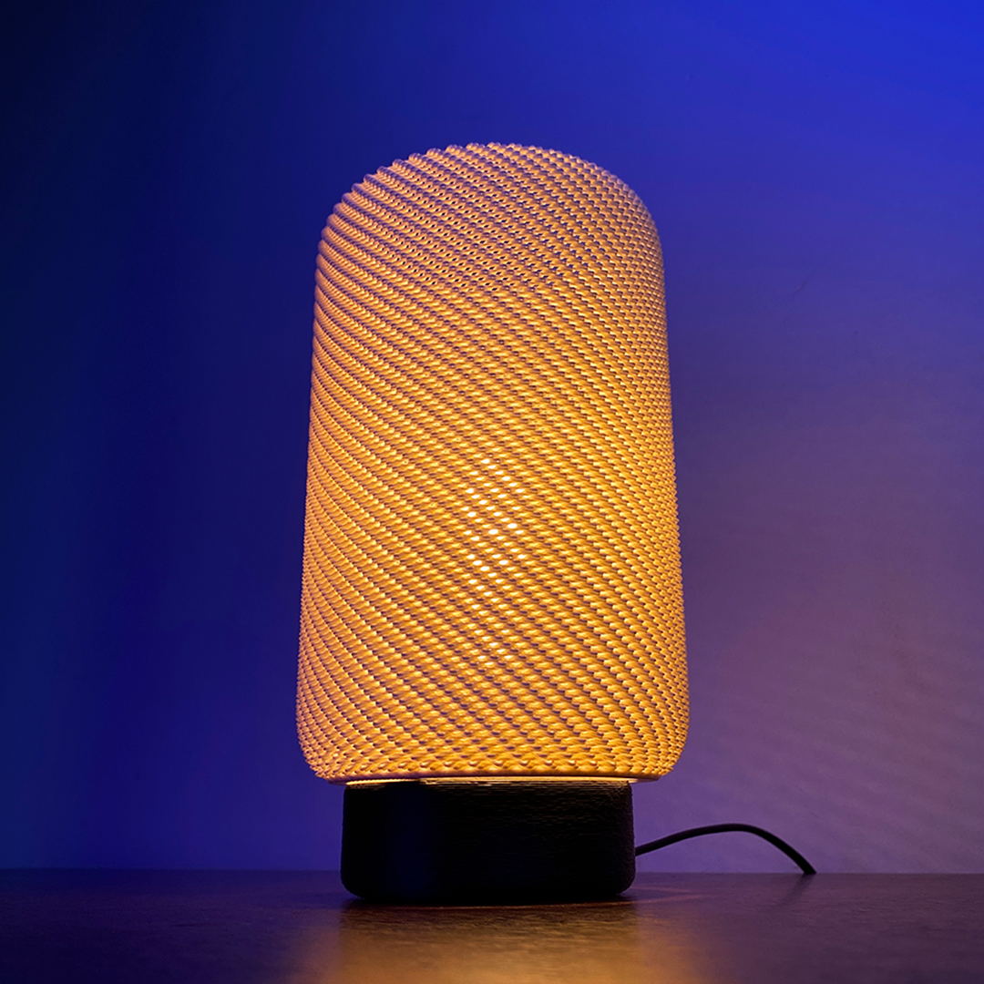EVE Table Lamp with a soft orange glow, featuring a textured cylindrical design, set against a deep blue background for a contemporary lighting effect.