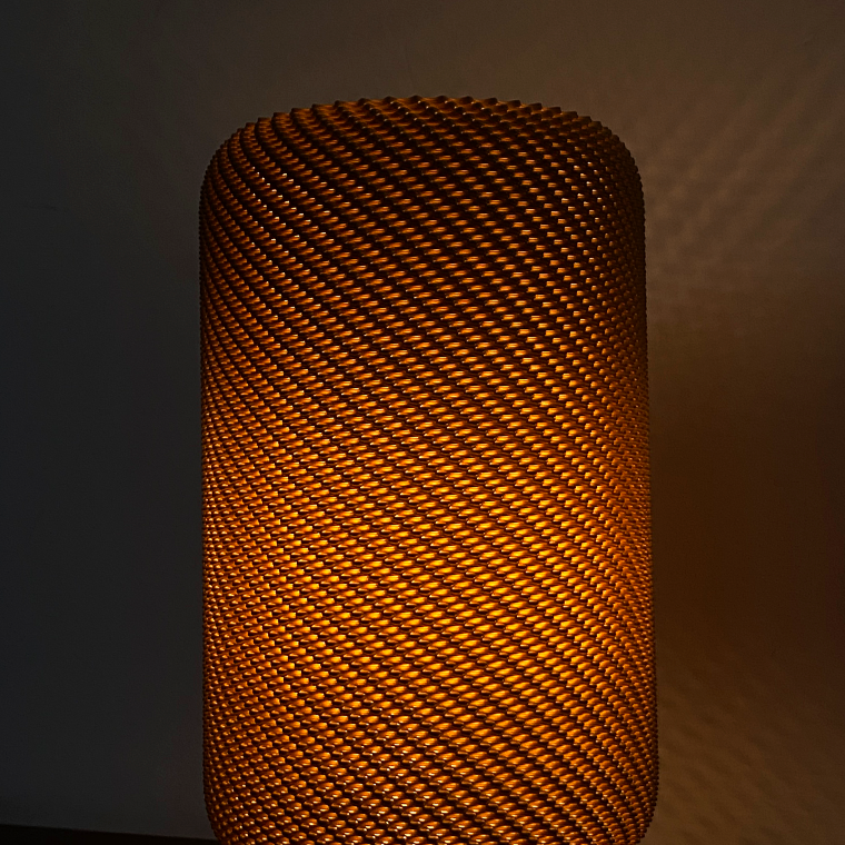 Textured EVE Table Lamp radiating a warm orange light, designed for modern interiors, with intricate patterns creating interesting shadows.