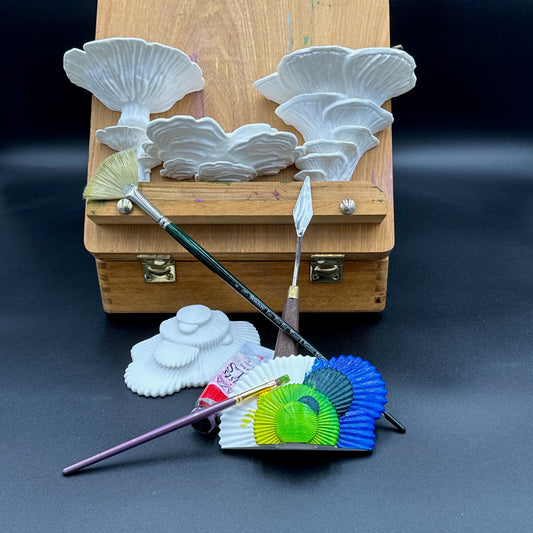 Creative arrangement of fungus-inspired white shelving units and painting tools on a dark surface, suitable for artistic decor.