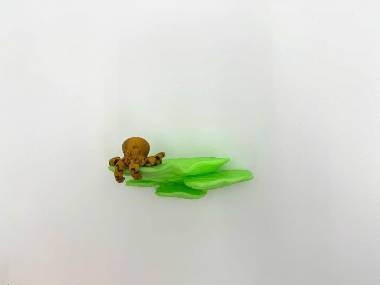 Close-up view of a glow in the dark Ostrea Mushroom Floating Shelf featuring a cute octopus figure, highlighting its unique shape and color.