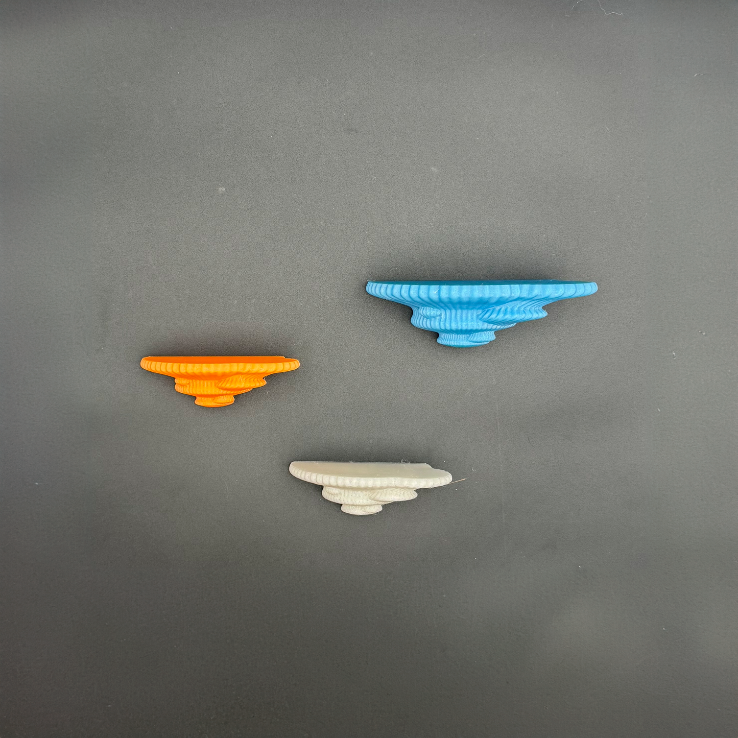 Three handcrafted floating shelves in vibrant colors: orange, blue, and white, highlighting unique design.