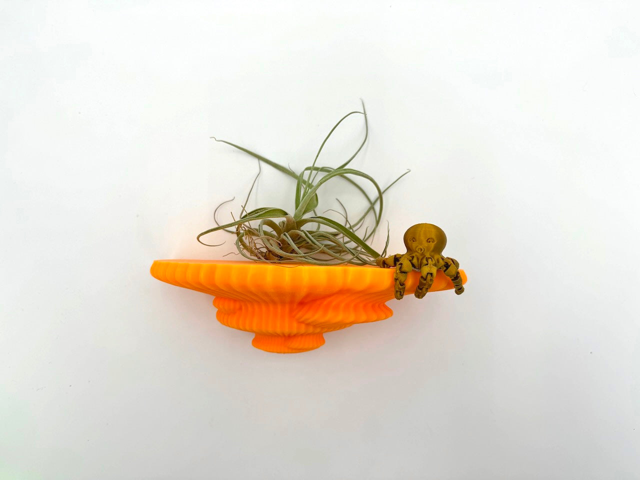 Bright orange Tinder Fungus mushroom floating shelf adorned with an air plant and a playful octopus figurine.