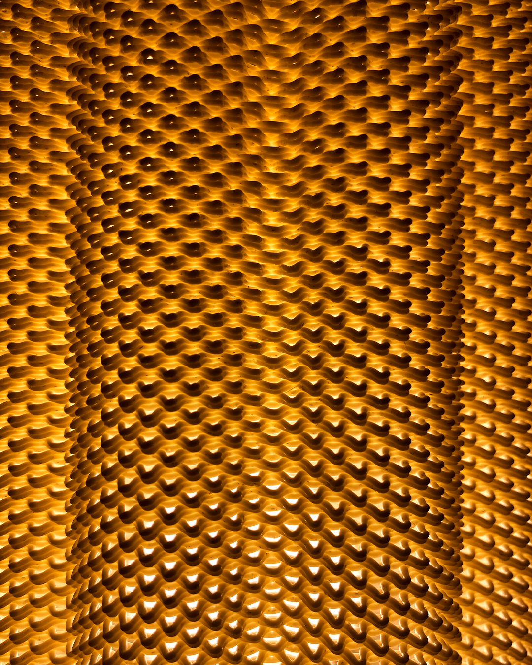 Close-up of the CARLA Table Lamp's intricate textured shade in warm yellow light, highlighting its unique design and beautiful light diffusion.