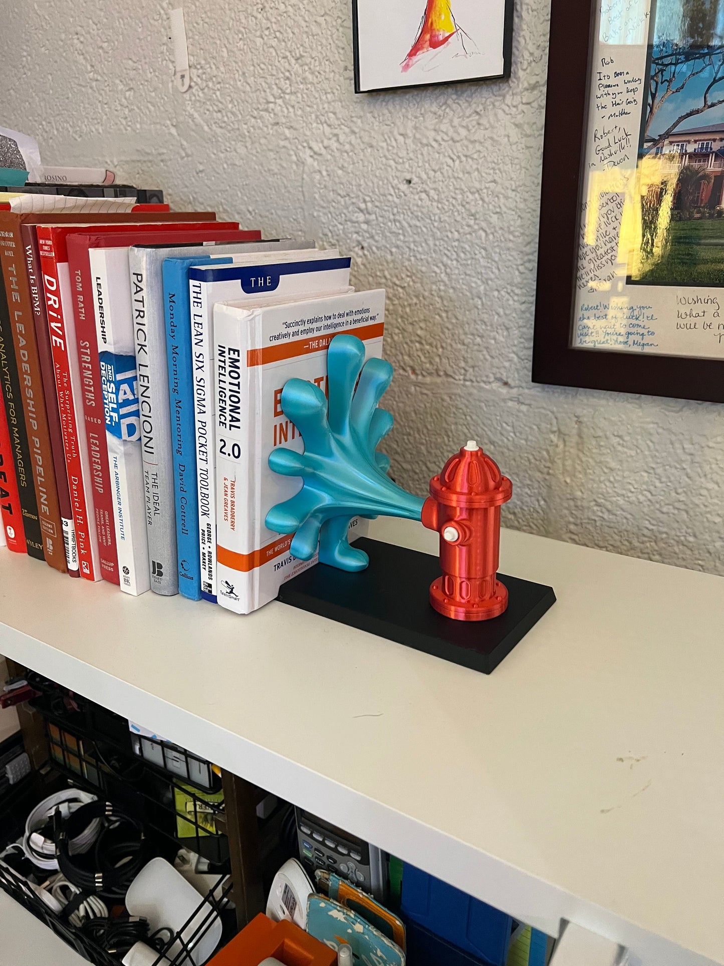 Brightly colored fire hydrant book end in red and turquoise placed among books on a shelf, adding a playful touch to a cozy reading corner.