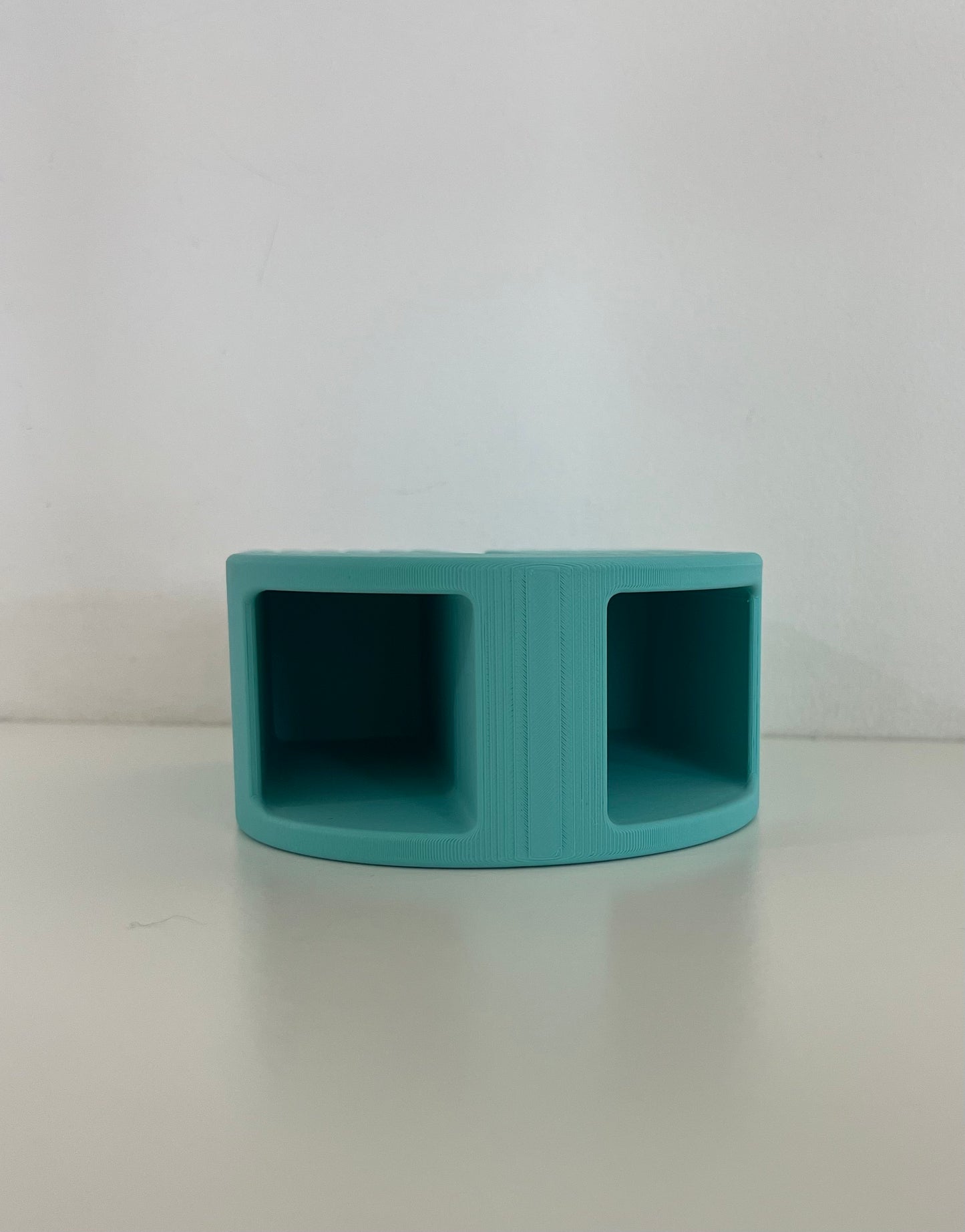 Minimalist turquoise organizer with two compartments, designed for storing office supplies or small items on a clean desk.