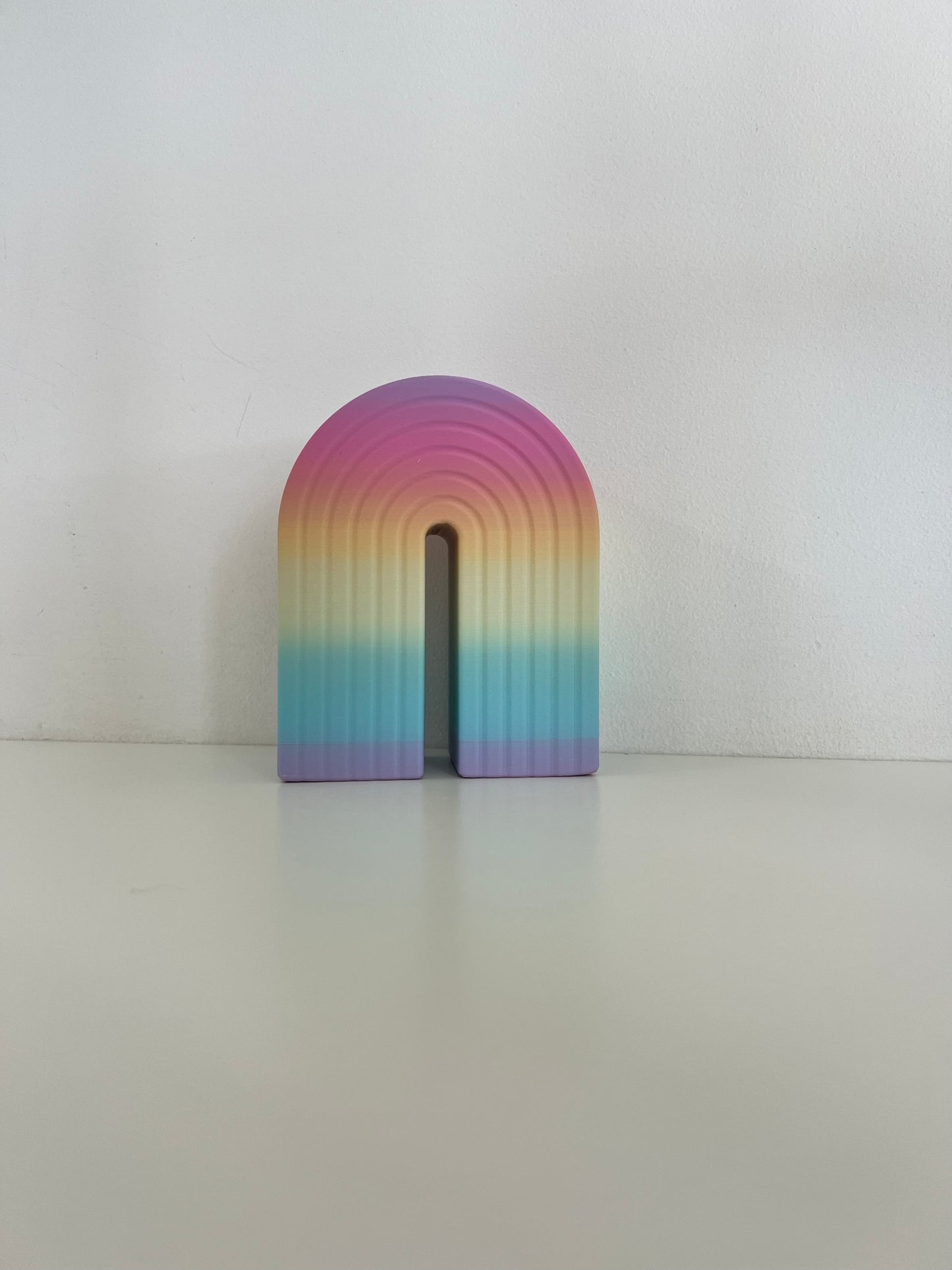Charming gradient rainbow bookend in pastel colors, transitioning from pink to blue, perfect for stylishly organizing books.