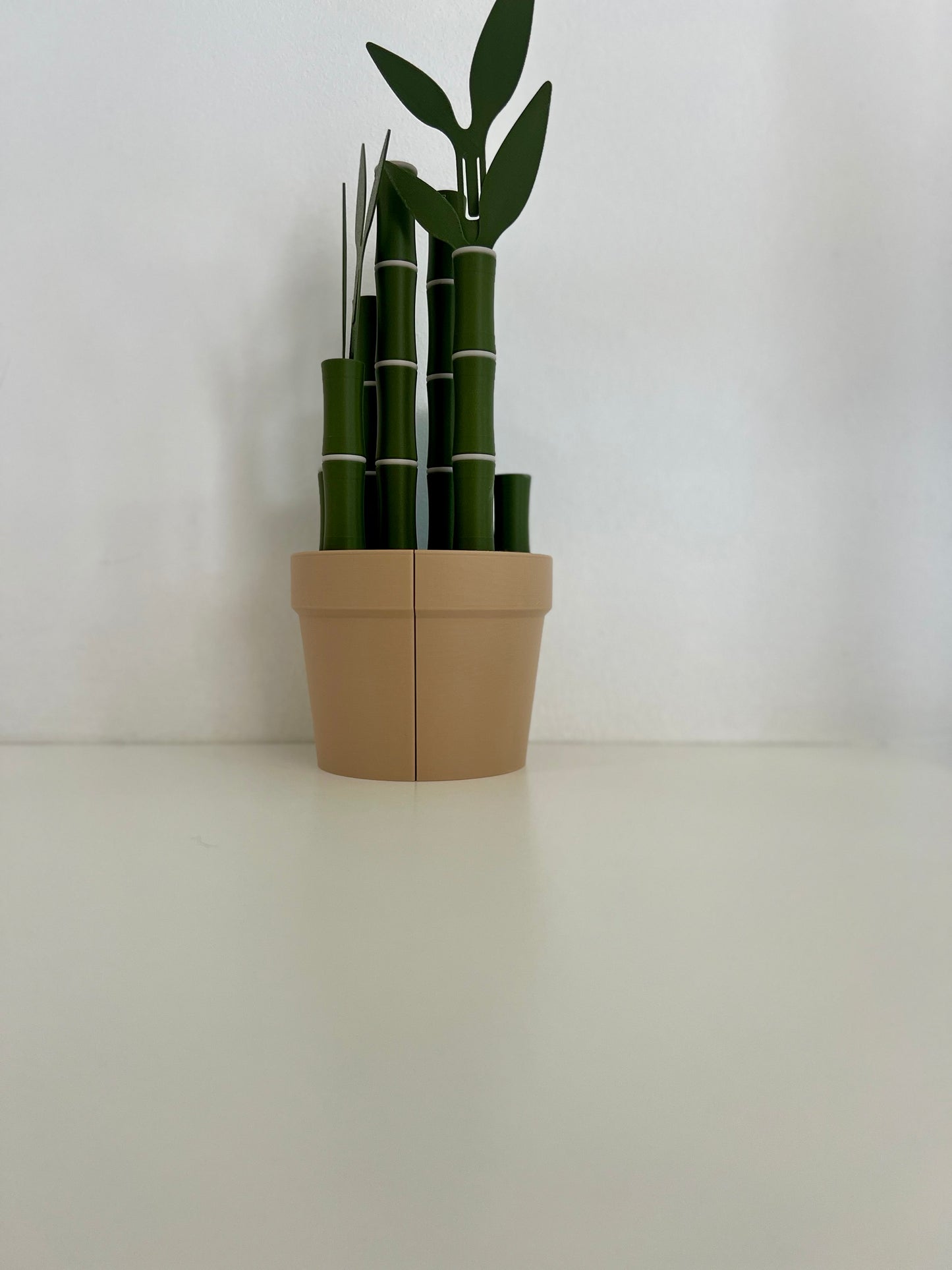 A close-up of a stylish bamboo potted plant, showcasing the unique design of bamboo sticks and leaves in a beige pot.