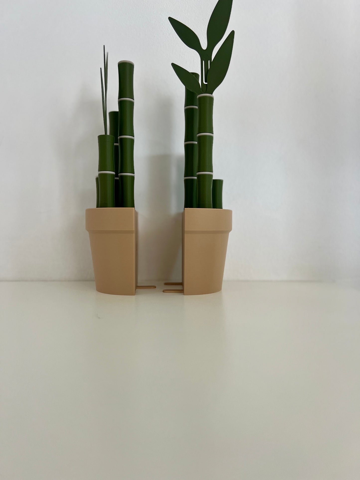 Two bamboo bookends displayed together, each with green bamboo sticks and leaves, offering a modern aesthetic on a white tabletop.