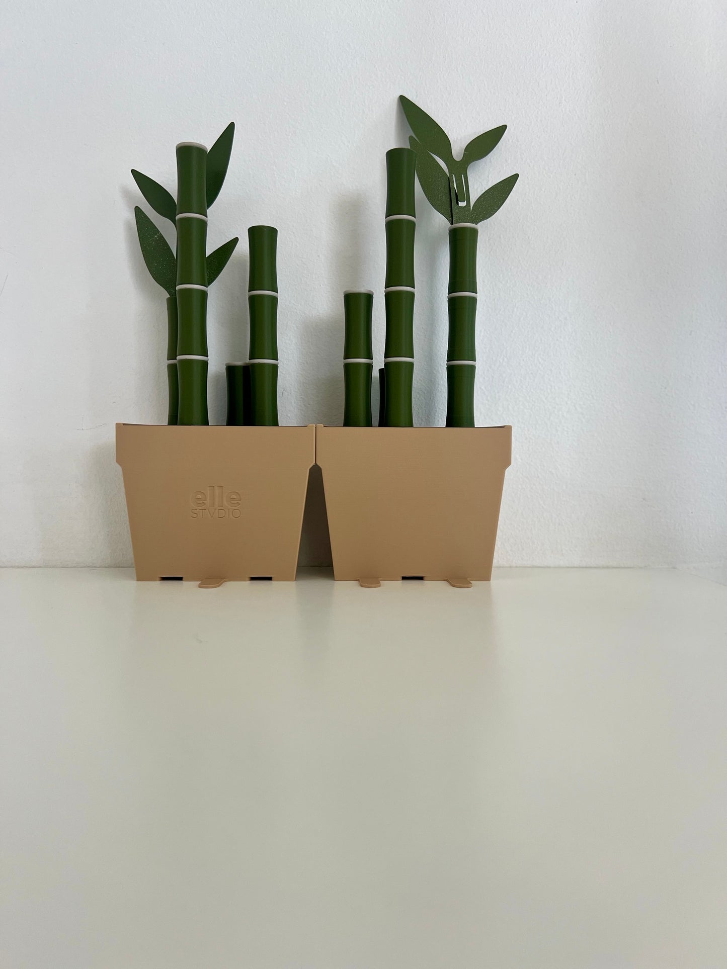 Two potted bamboo bookends side by side, featuring vibrant green bamboo and leaves, set against a clean white background for a chic look.