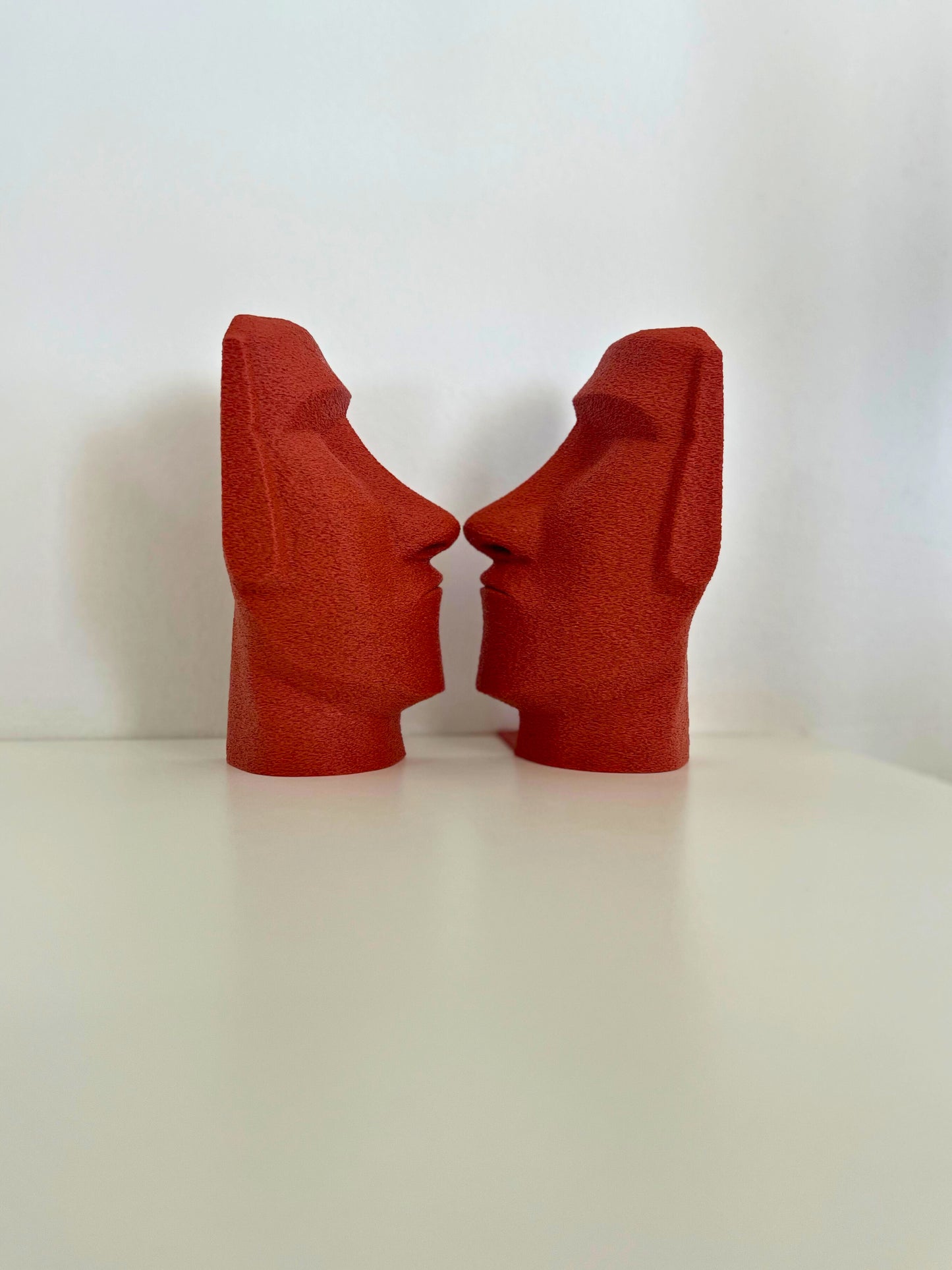 Pair of red Moai bookends displaying a modern design, holding up books with an eye-catching look.