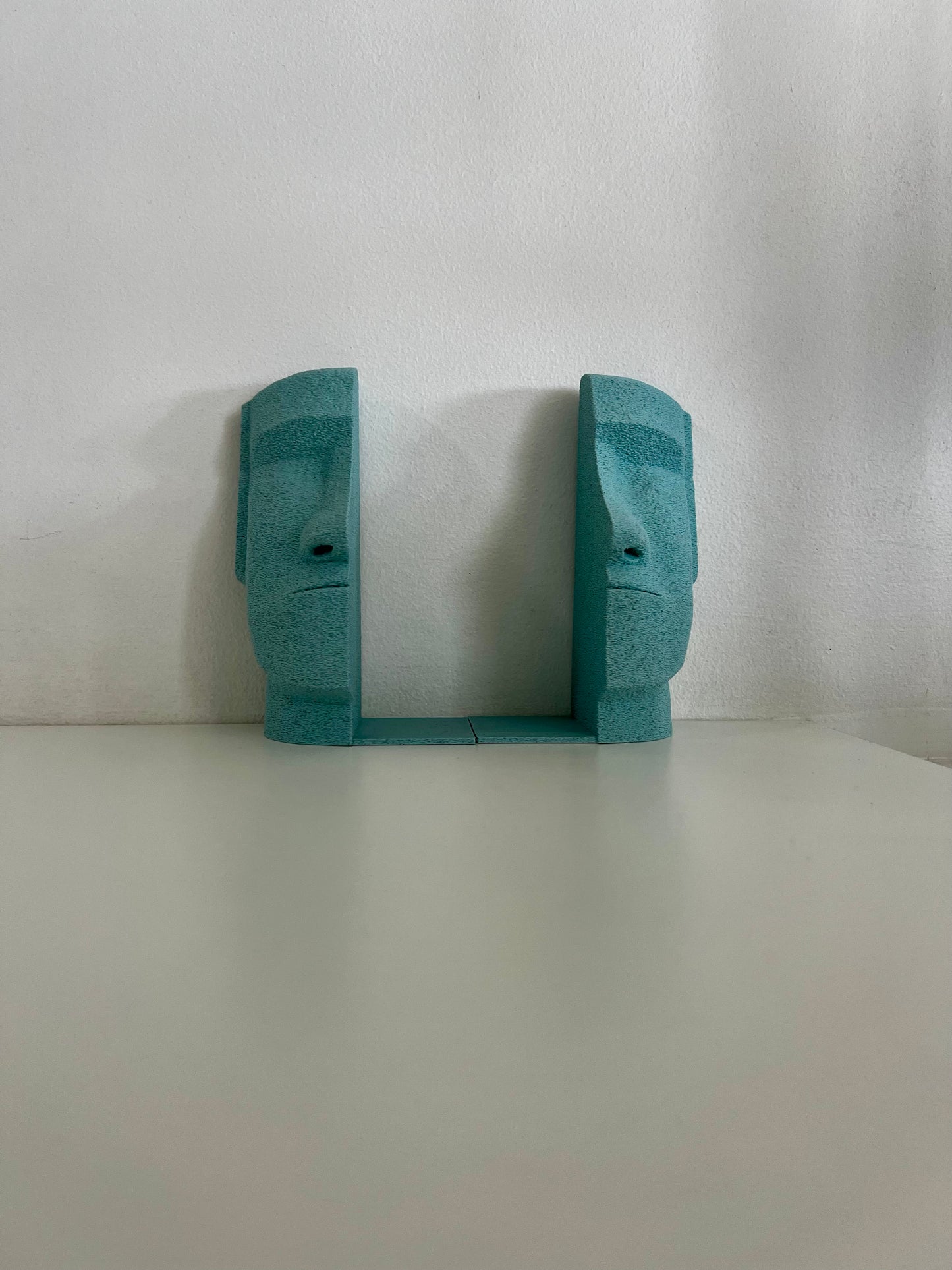Front view of matching turquoise Moai bookends, showcasing their sculptural design on a clean surface.