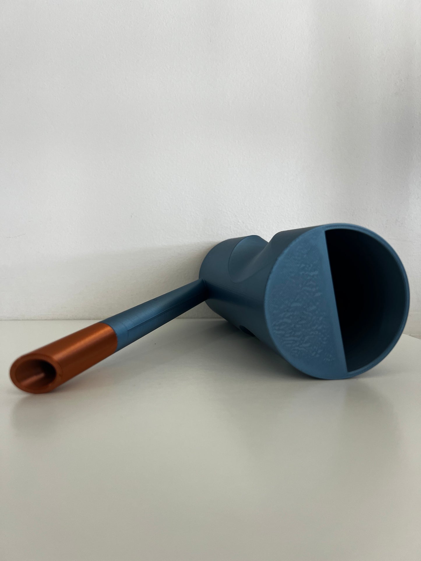 Two watering cans in varied shades, highlighting their striking forms and removable spouts, arranged aesthetically.