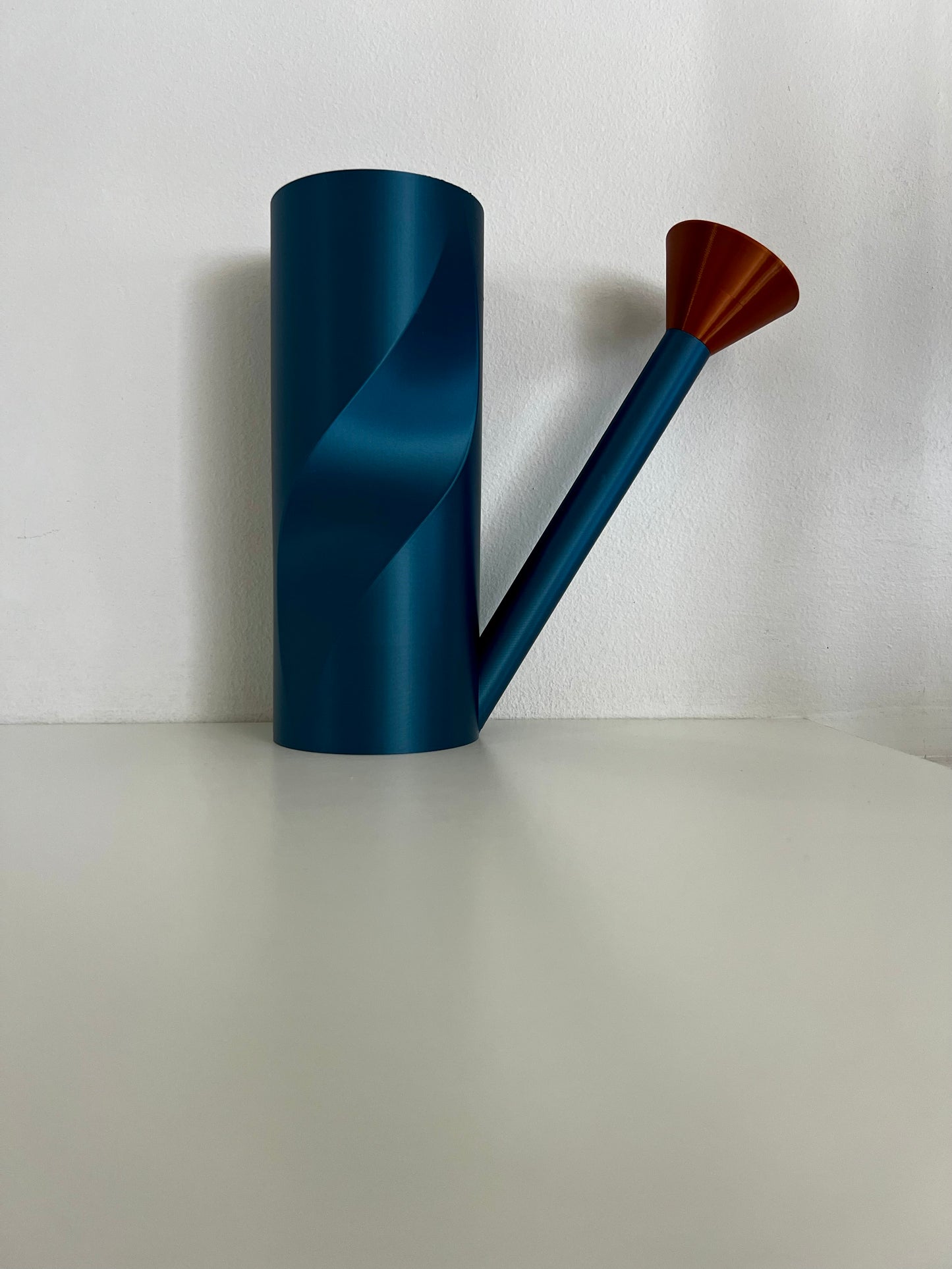 An elegant blue watering can next to a pair of captivating copper spouts, showcasing their innovative design.