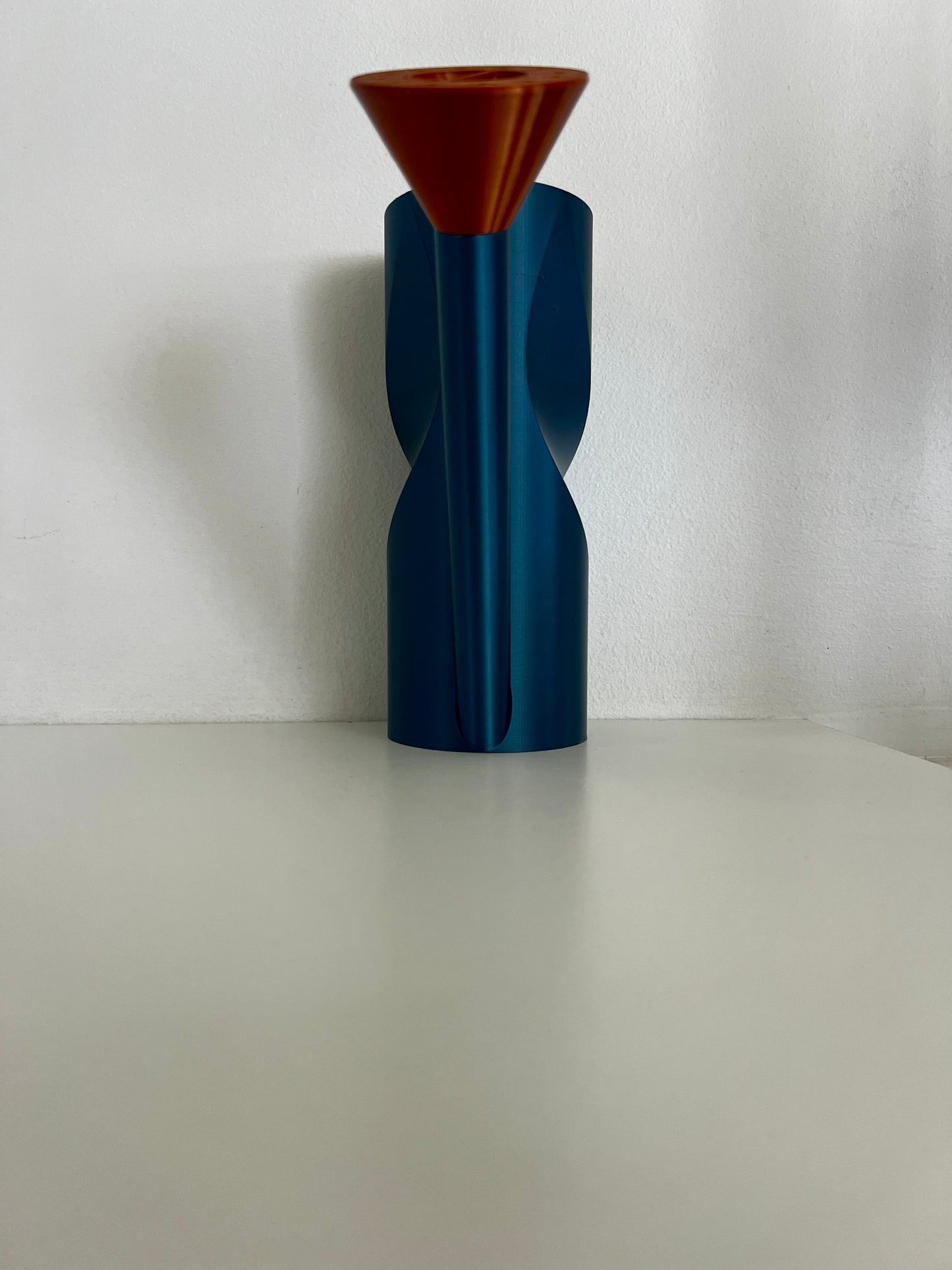 A vibrant blue watering can with a unique twist design, positioned on a clean background with a small copper spout.