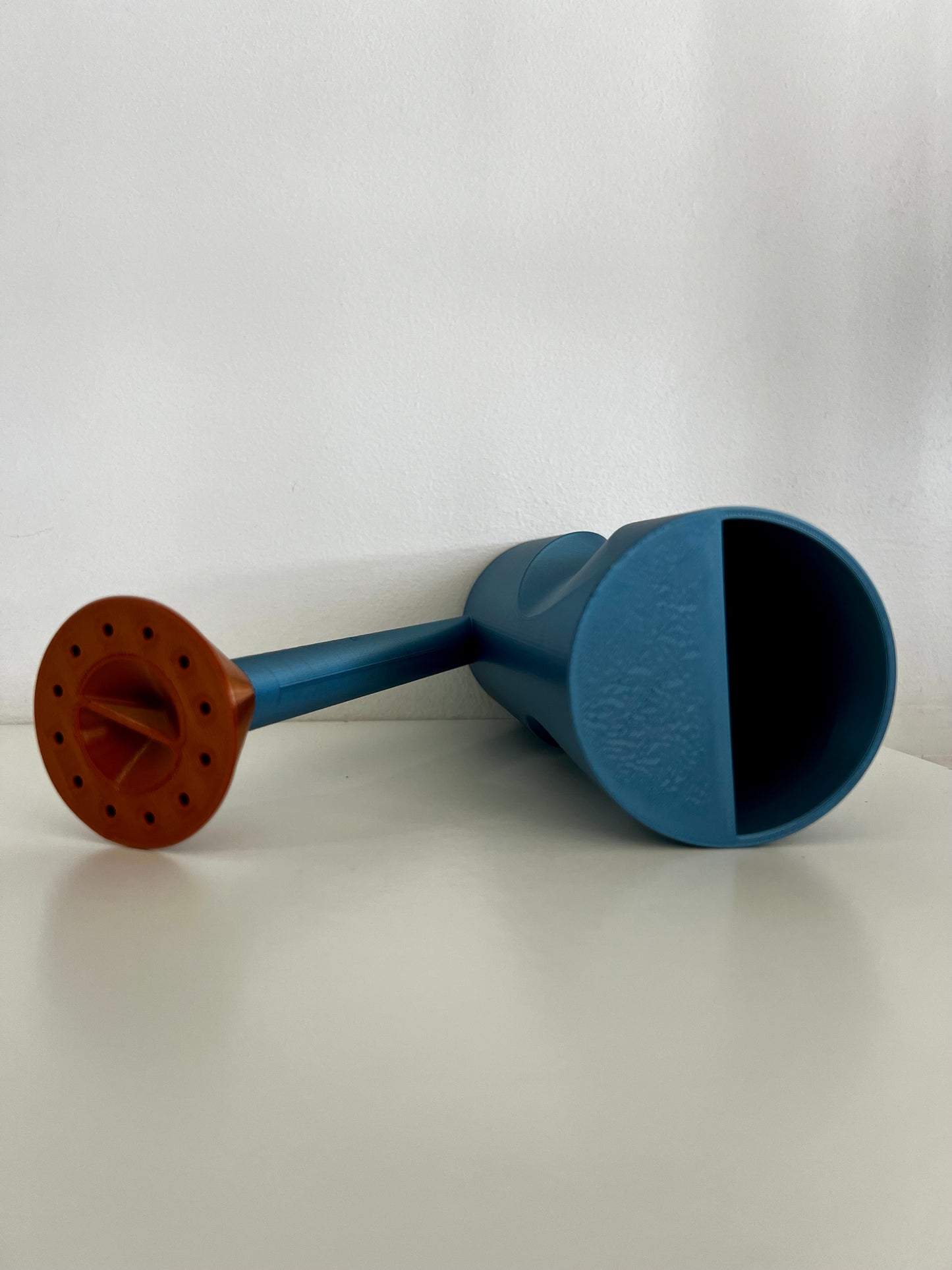 A unique matte black watering can with a copper-spouted design, elegantly displayed on a white surface.