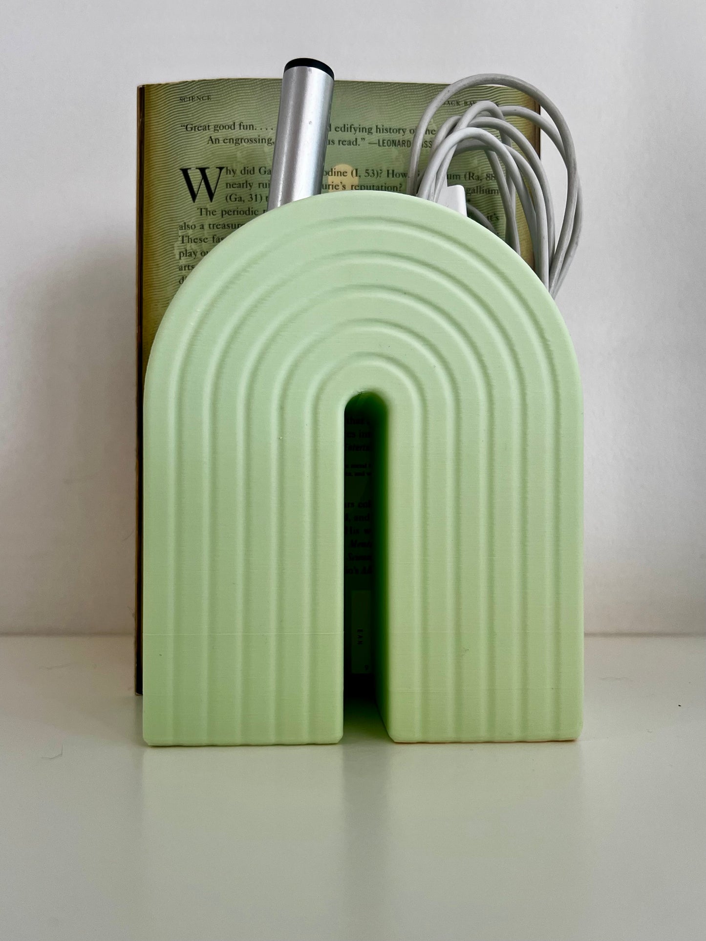 Trendy pastel green rainbow organizer displaying a blend of function and style, holding a book and a pen on a neat desk setup.