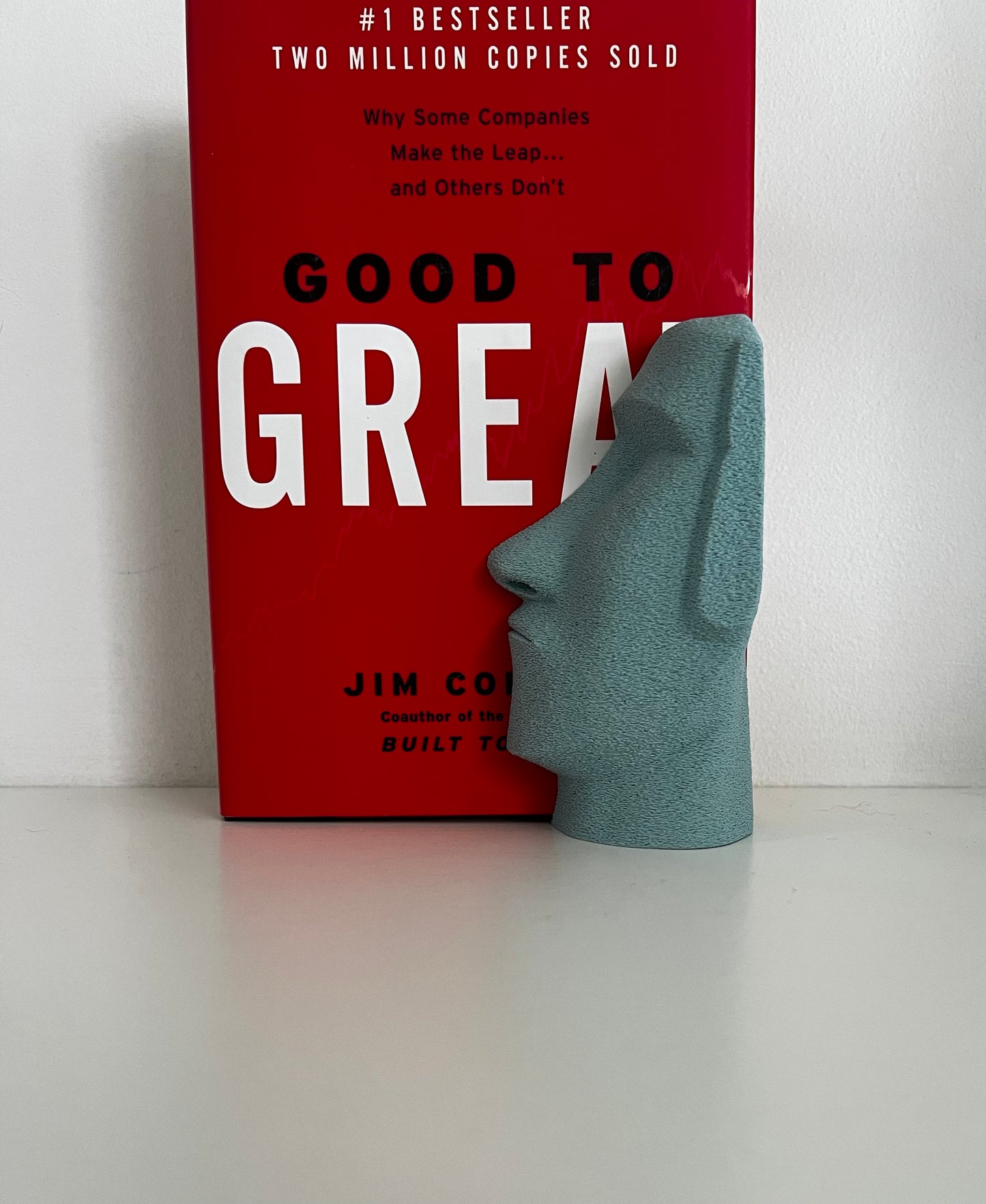 Turquoise Moai bookend featured alongside a popular business book, enhancing its display with a modern touch.