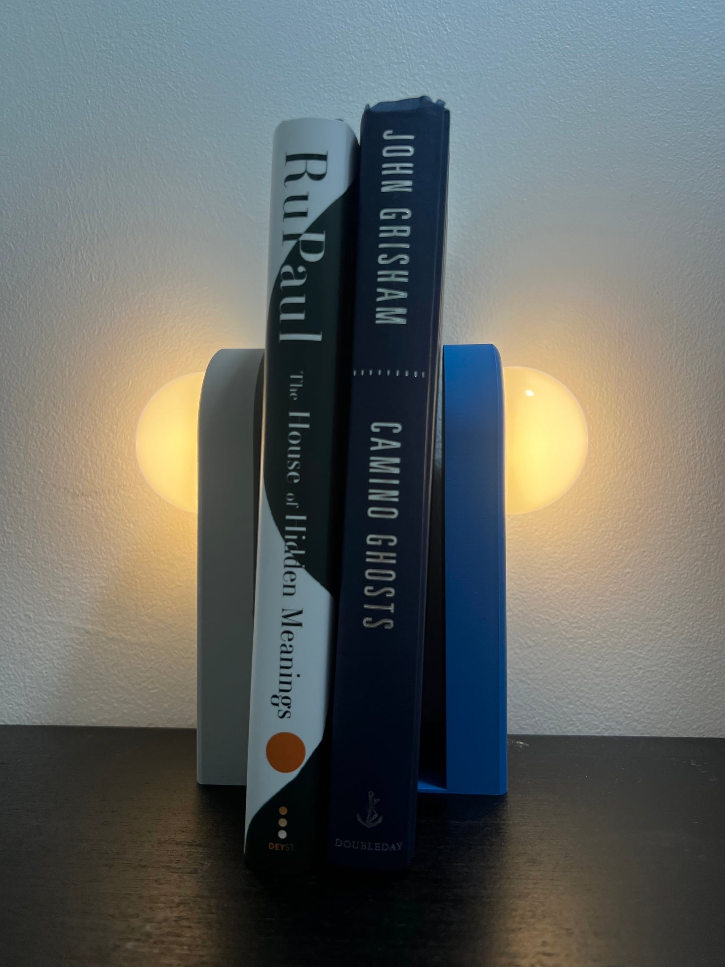 Lighted bookend in stylish design holding books, illuminated softly to enhance home decor.