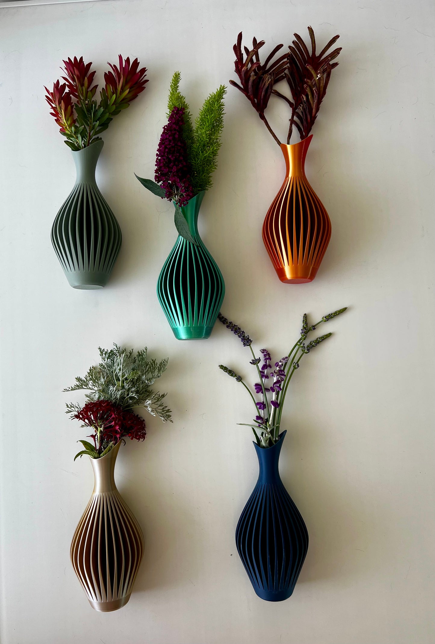 Colorful wall-mounted vases in a range of stylish designs filled with flowers, adding vibrancy to decor.