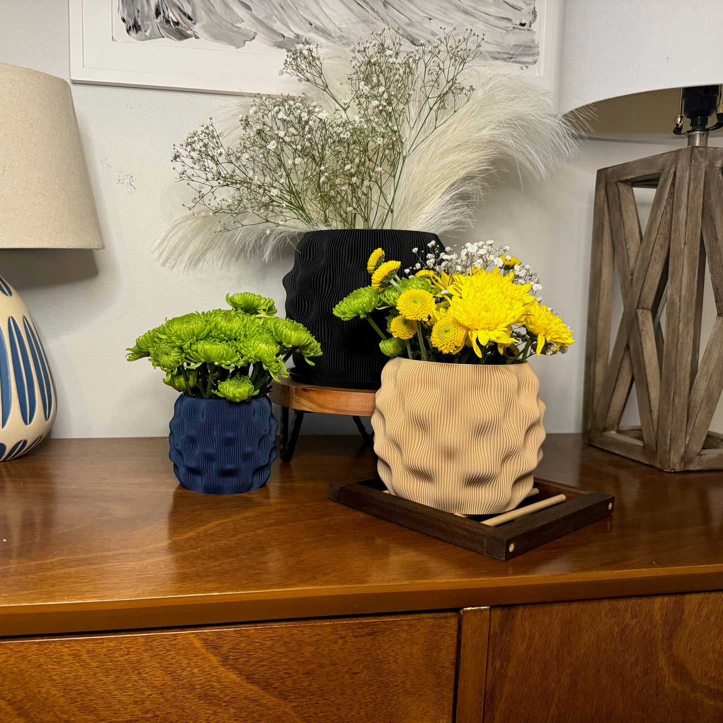 A charming arrangement of colorful dimpled planters with flowers on a wooden surface, set against a cozy indoor backdrop.