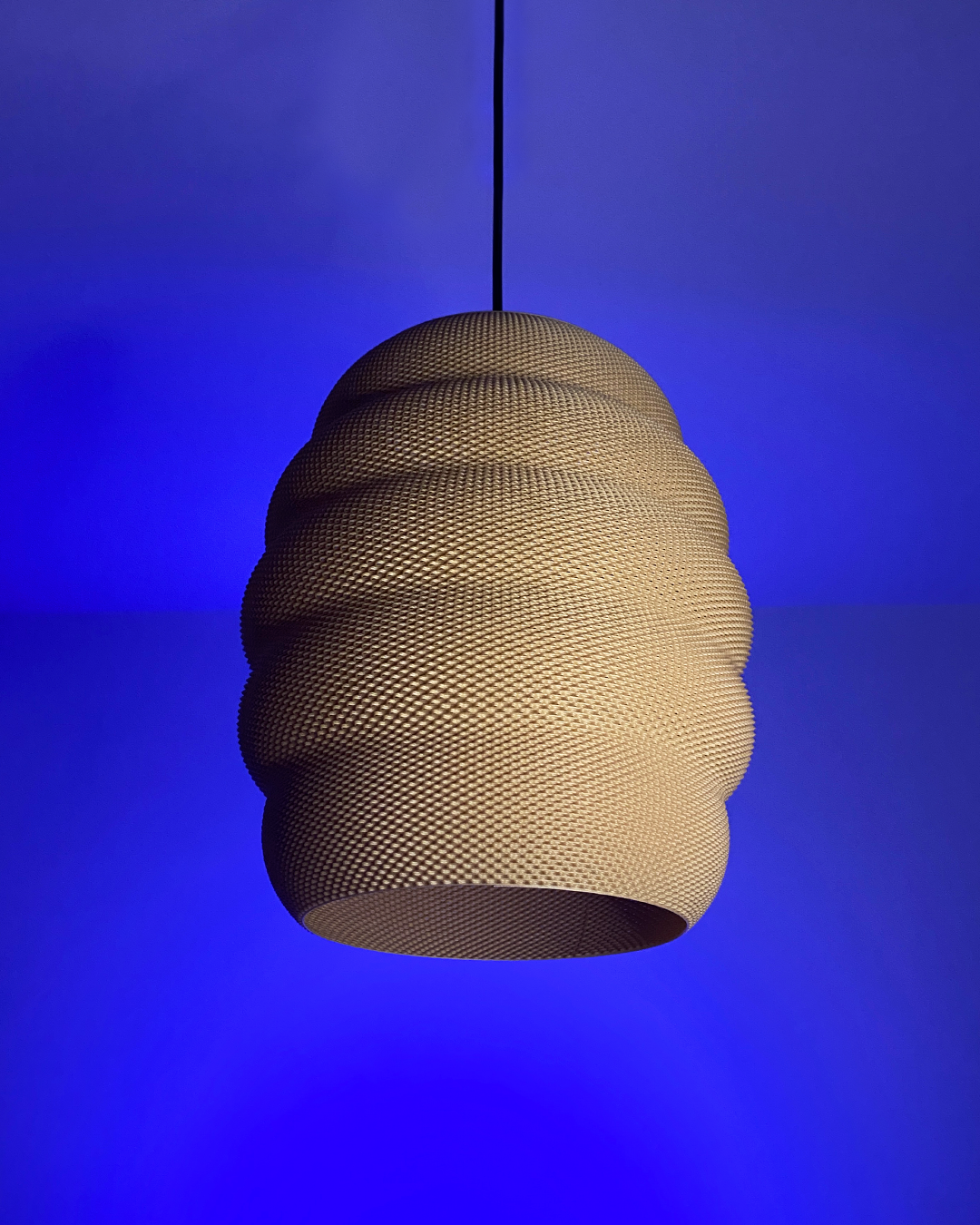 A beehive-shaped pendant light hangs against a deep blue wall, casting no visible light.